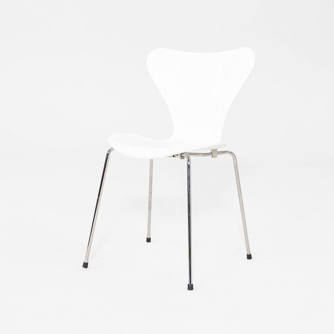 This is a Series 7 Chair, originally designed by Arne Jacobsen in 1955. This particular example was produced by Fritz Hansen in Denmark in 2024. The chair features a molded ash veneer shell that is painted white and paired with polished chrome