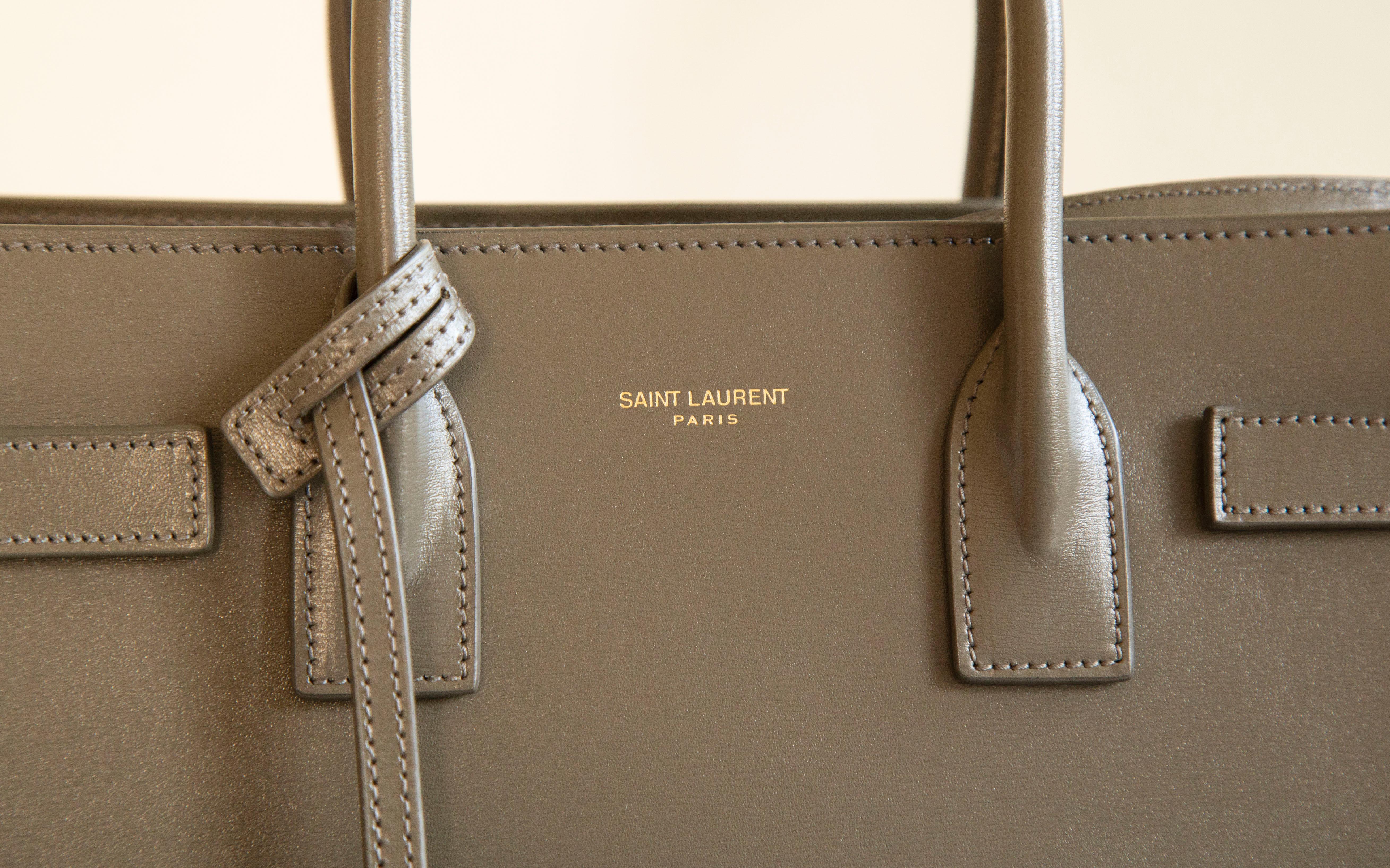 Saint Laurent’s khaki-green Sac de Jour Baby top handle bag/shoulder bag/crossbody bag. The interior is divided into two  compartments divided by a removable zipped pochette.  The hardware is gold tone. The strap is adjustable (max. 120 cm ) and