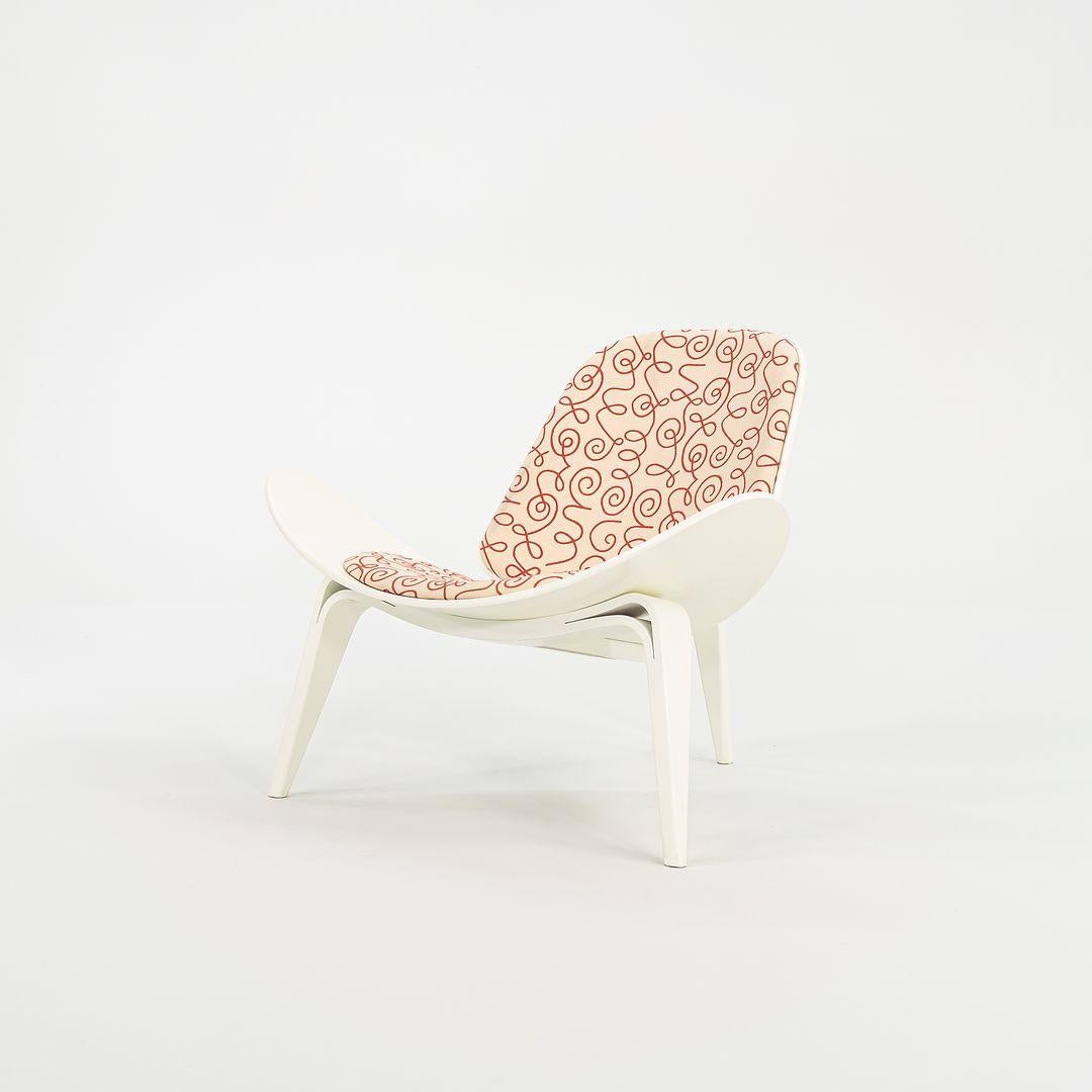 In vendita c'è una sedia a conchiglia CH07, con struttura in impiallacciatura bianca e cuscino in tessuto a fantasia rossa. La sedia, disegnata da Hans Wegner e prodotta da Carl Hansen & Son in Danimarca, risale al 2021 circa ed è garantita come