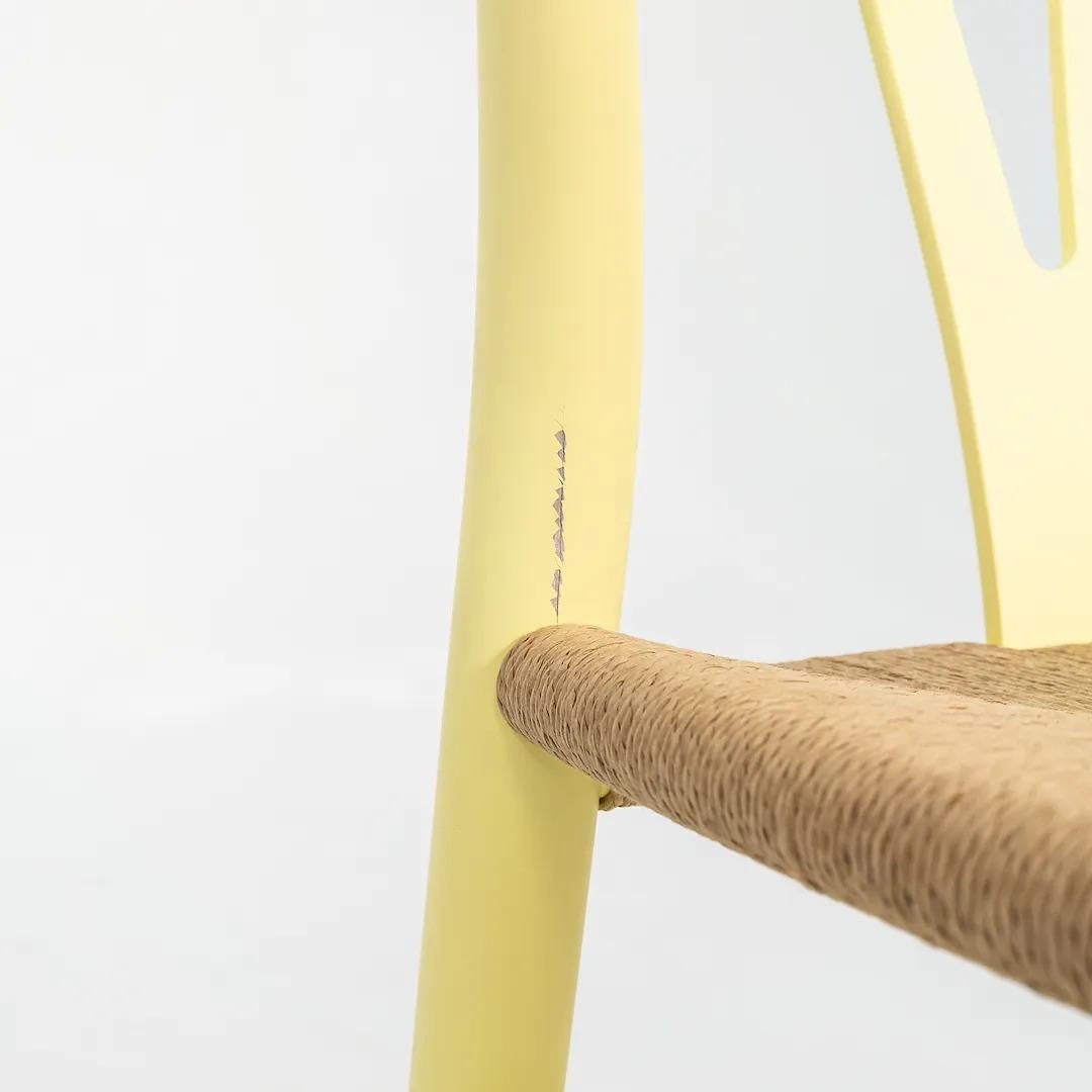 Dies ist ein CH24 Wishbone Dining Chair mit einem Gestell aus massivem Buchenholz, gelb lackiert in Hollyhock und einem Sitz aus Naturpapierkordel. Dieser Stuhl hat eine unmarkierte Schachtel, scheint aber in der Farbe Hollycock von Ilse Crawford