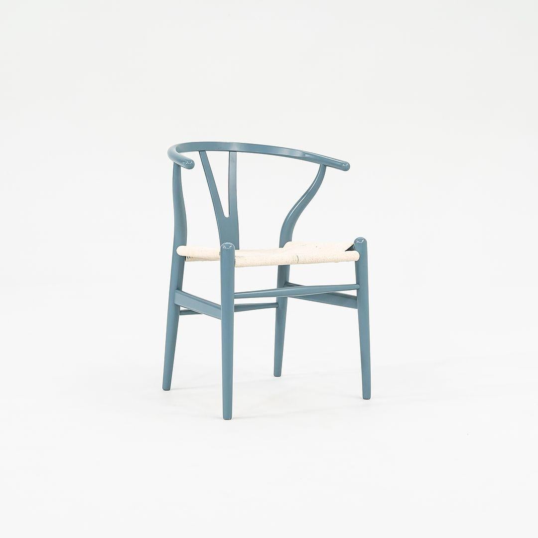 This is a CH24 Wishbone Dining Chair made with a slate blue beech wood frame and white paper cord seat. Designed by Hans Wegner and produced by Carl Hansen & Son in Denmark, the chair dates to circa 2021 and is guaranteed as authentic. Condition is