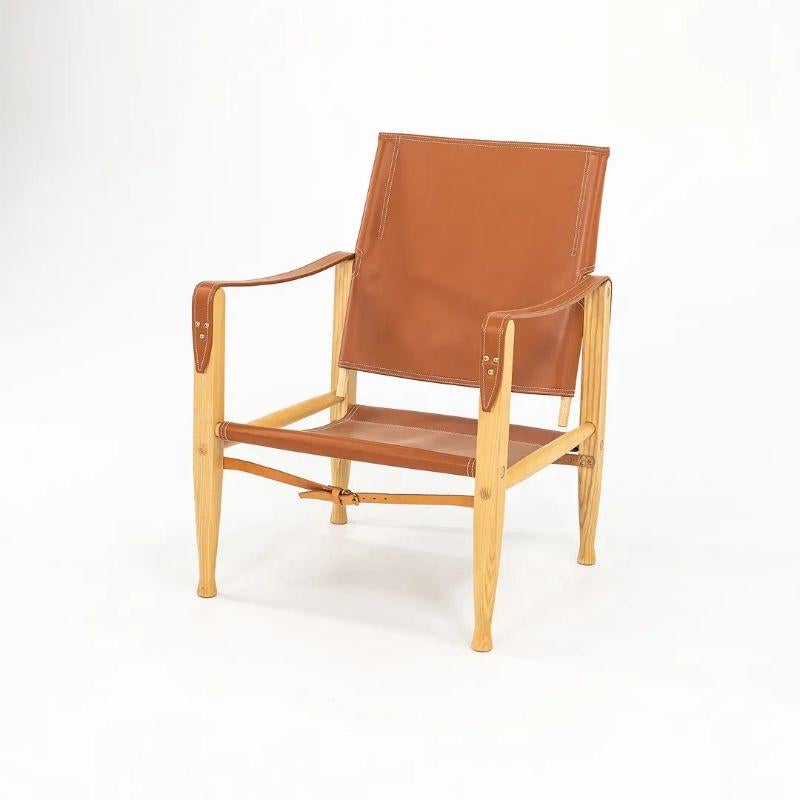 This is a KK47000 Safari Lounge made with an oiled ash wood frame and cognac leather seat. The chair, designed by Kaare Klint and produced by Carl Hansen & Son in Denmark, dates to circa 2021 and is guaranteed as authentic. Condition is very good to