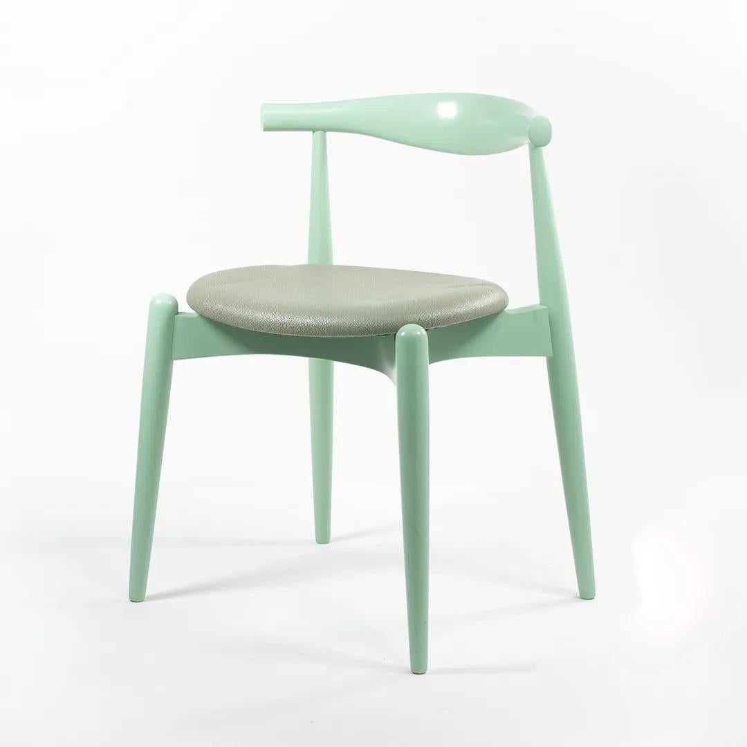 Il s'agit d'une chaise de salle à manger CH20 Elbow fabriquée avec un cadre en hêtre massif, peint en vert menthe, et un siège en cuir Chagrin vert (commandé COL ou Customers Own Leather via Edelman leather très probablement). La chaise, conçue par