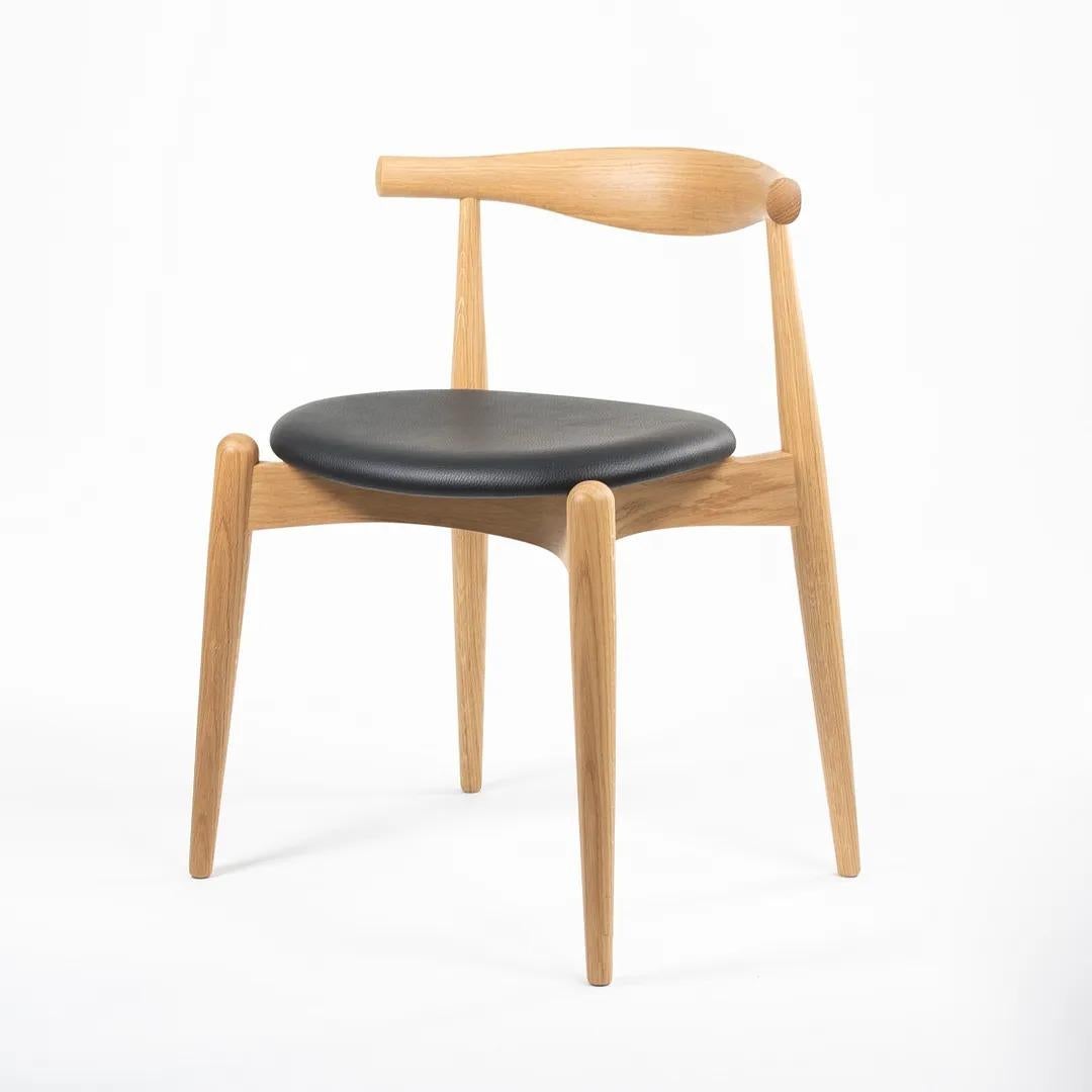 This is a single (two are available, though the price is for each chair) CH20 Elbow Dining Chair made with a solid oak frame and black leather seat. The chair, designed by Hans Wegner and produced by Carl Hansen & Son in Denmark, dates to circa 2021