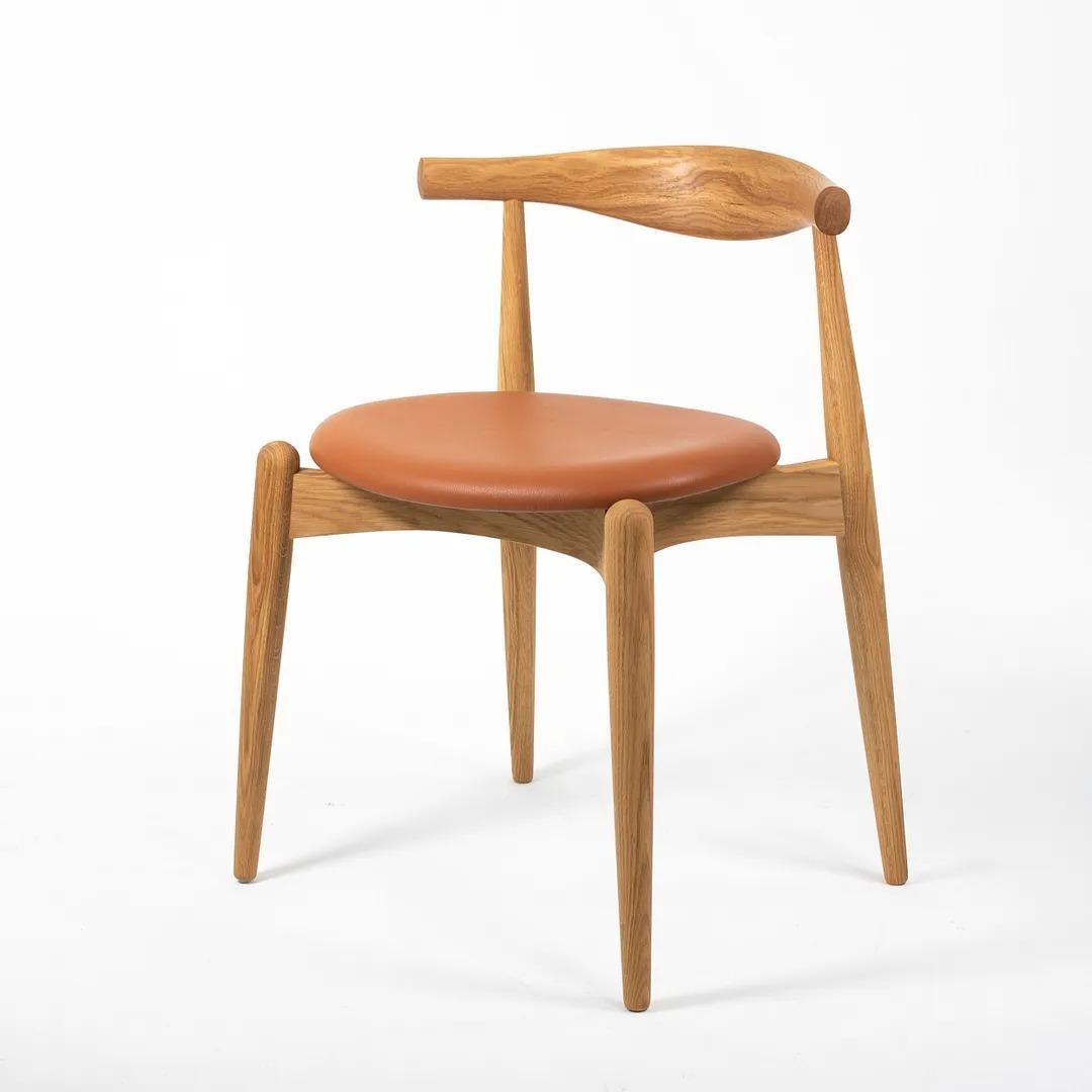 This is a single (three are available, though priced individually) CH20 Elbow Dining Chair designed by Hans Wegner and produced by Carl Hansen & Son in Denmark. The chair is made with a solid oiled oak frame and leather seat. The leather appears to