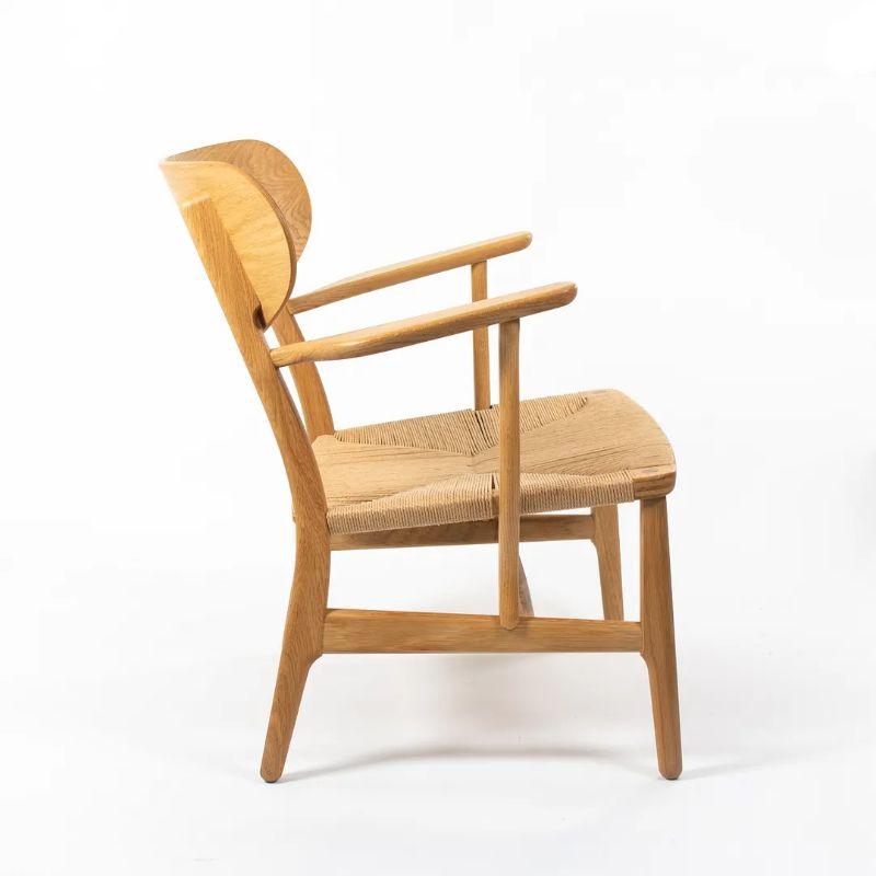 This is a CH22 Lounge Chair made with a solid lacquered oak frame and natural paper cord seat. The chair, designed by Hans Wegner and produced by Carl Hansen & Son in Denmark, dates to circa 2021 and is guaranteed as authentic. Condition is