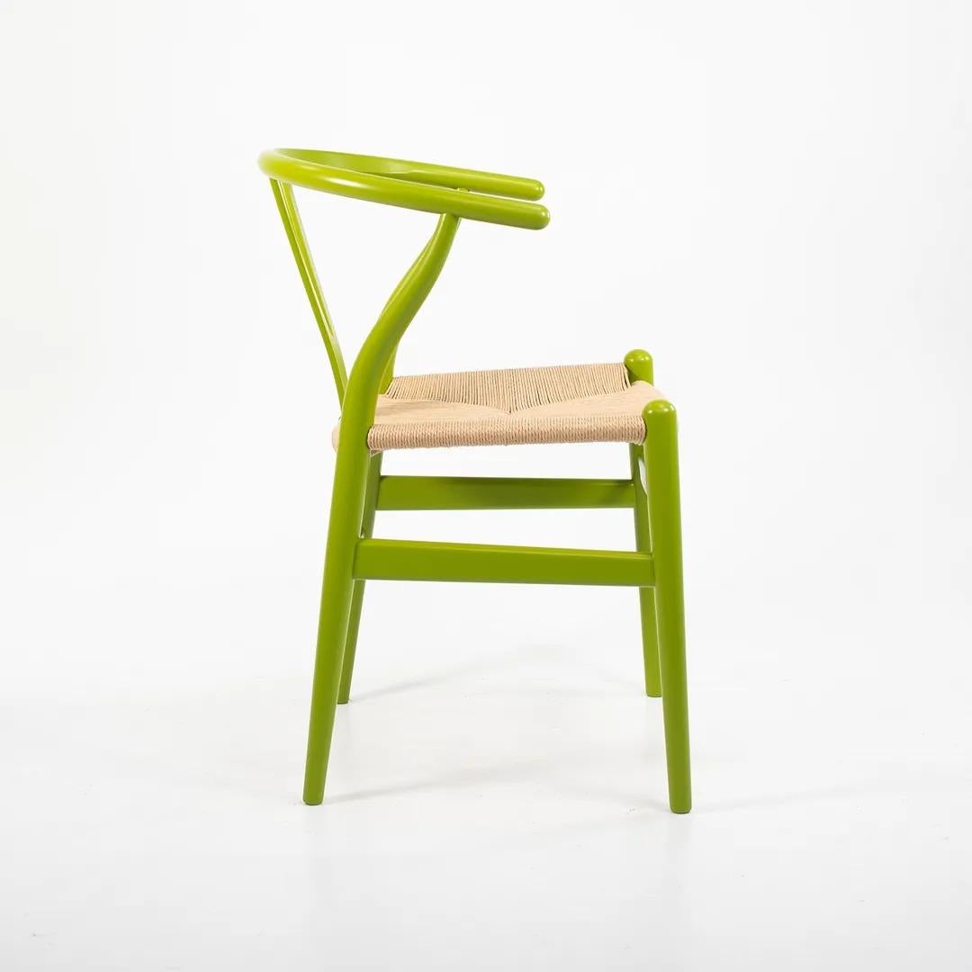 These are four (sold individually) Wishbone chairs, designed by Hans Wegner and produced by Carl Hansen & Son in Denmark. The chairs are made with a solid beech frame, painted bright green with a natural paper cord seat. These chairs date to circa