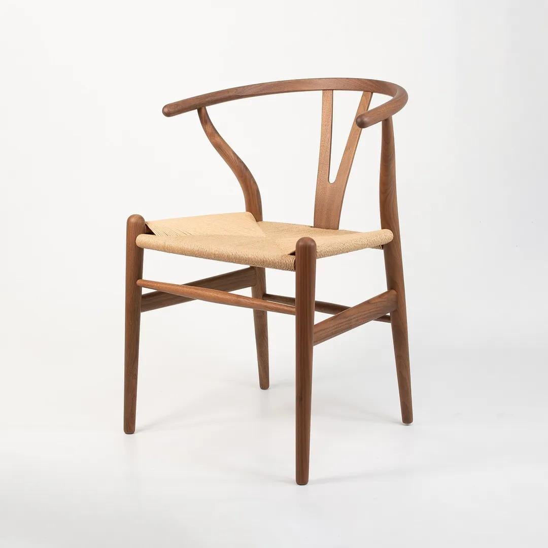 Il s'agit d'une chaise de salle à manger CH24 Wishbone, conçue par Hans Wegner et produite par Carl Hansen & Son au Danemark. La chaise est composée d'un cadre en noyer massif et d'une assise en corde de papier naturel. Cette chaise a été produite