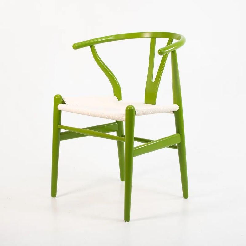 Listed for sale are three (sold separately) Wishbone dining chairs, designed by Hans Wegner and produced by Carl Hansen & Son in Denmark. The chairs are made with a solid beech frame, painted bright green with a white paper cord seat. These chairs