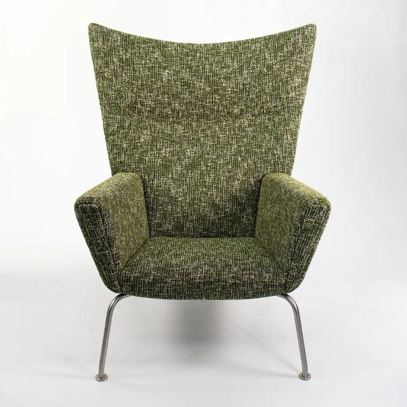 Listed for sale is a CH445 Wing Lounge Chair made with a stainless steel frame and green fabric, designed by Hans Wegner and produced by Carl Hansen & Son in Denmark. The chair dates to 2021 and is guaranteed as authentic. Condition is excellent