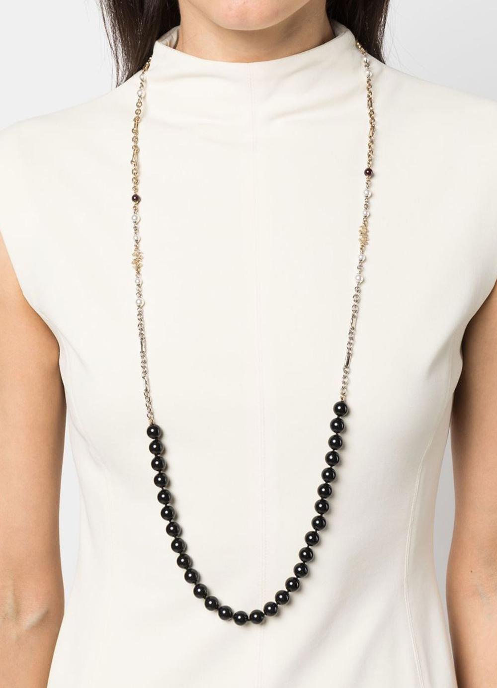 Schwarze, perlenbesetzte, lange Halskette von Chanel mit abgerundeten, schwarzen Perlen, dem charakteristischen, ineinandergreifenden CC-Logo der Marke, einem Federringverschluss mit Chanel-Lochung und einem freien Charme auf der Rückseite.
Maxi