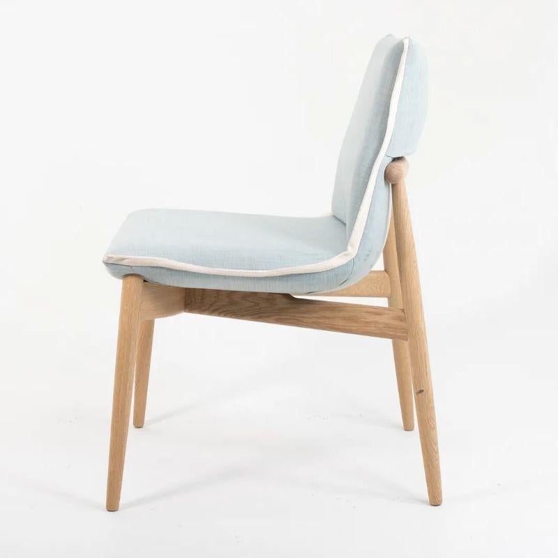 This is an EOO4 Embrace dining chair with a solid oak frame and a light blue down seat with white trim. The chair was designed by EOOS and produced by Carl Hansen & Son in Denmark. The chair was produced circa 2020 and is guaranteed as