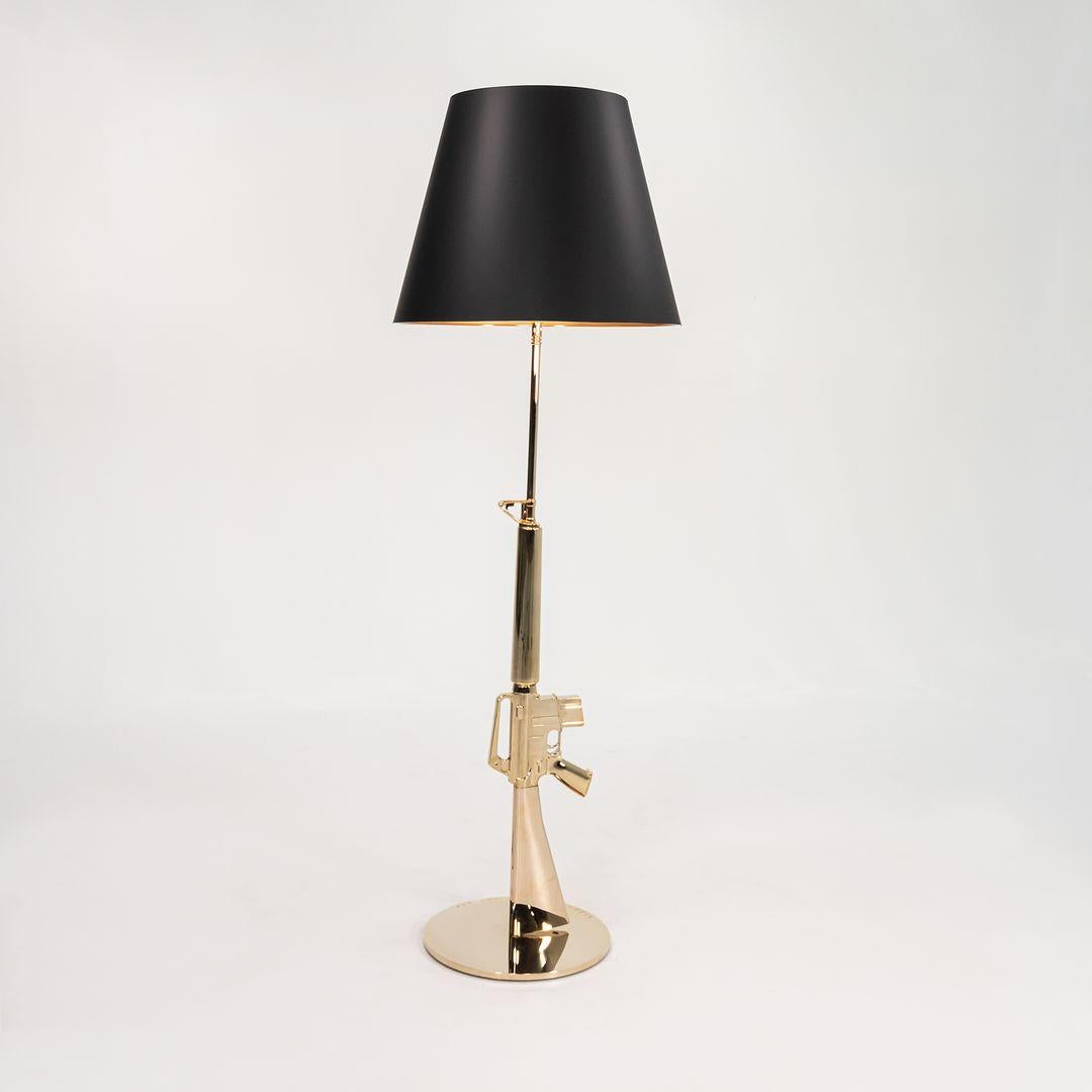 Listed for sale is a Gun Lounge Floor Lamp made with an 18K gold die-cast aluminum base and a black plasticized paper shade silkscreened in gold on the inside. The lamp was designed by Philippe Starck, produced by Flos¬†in Italy and dates to circa
