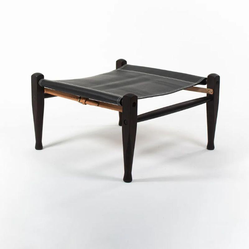 Listed for sale is a KK97170 Safari Footstool with solid ebonized ash wood frame and black leather seat. The footstool, designed by Esben Klint and produced by Carl Hansen & Son in Denmark, was produced circa 2021. It is guaranteed as