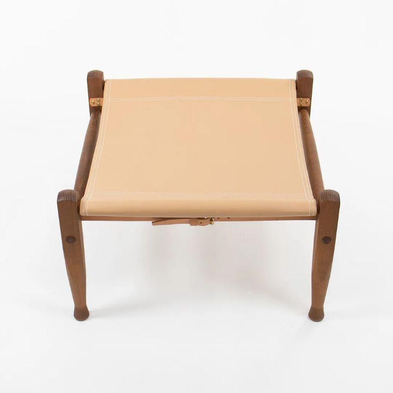 Listed for sale is a KK97170 Safari Footstool with a solid smoked ash frame and tan leather seat. The footstool, designed by Esben Klint and produced by Carl Hansen & Son in Denmark, was produced circa 2021 and is guaranteed as authentic. Condition