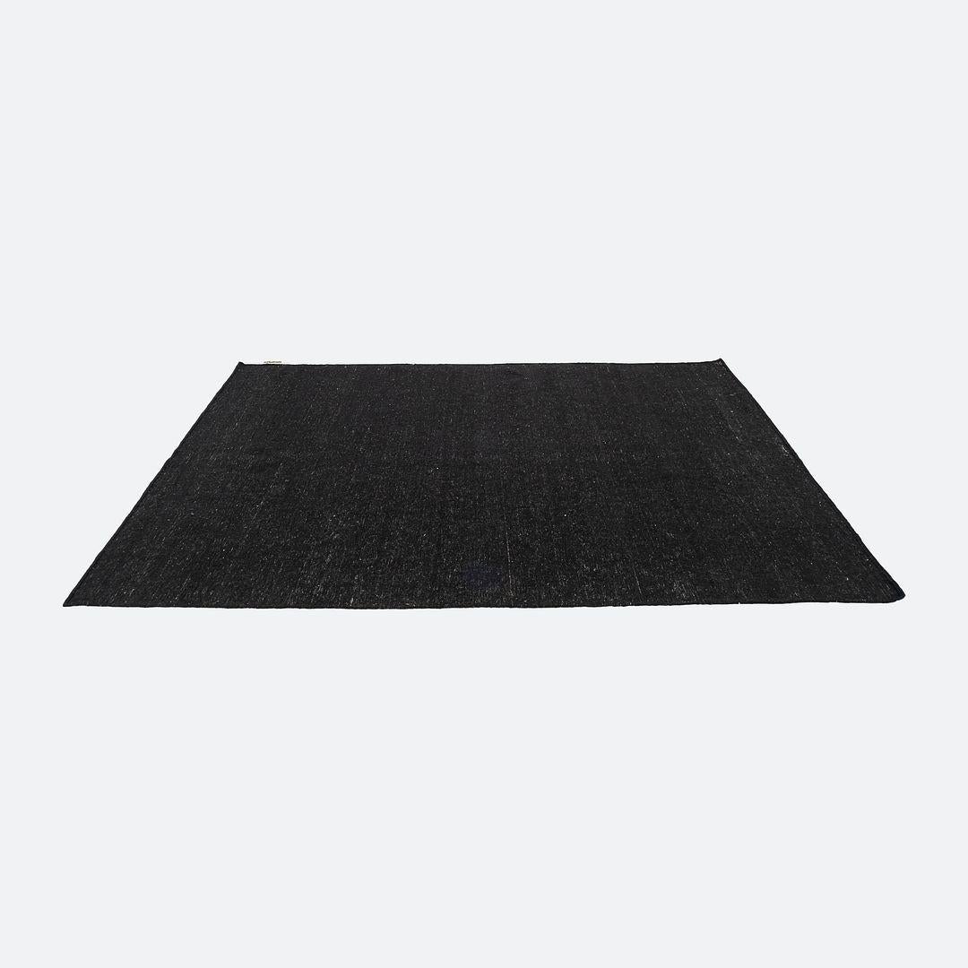 This is a Nomad Rug hand loomed with hand spun Afghan wool in a shade of black. The rug was designed by Nani Marquina and Ariadna Miquel and produced by Nanimarquina in India. It dates to circa 2022 and is guaranteed as authentic. Condition is very