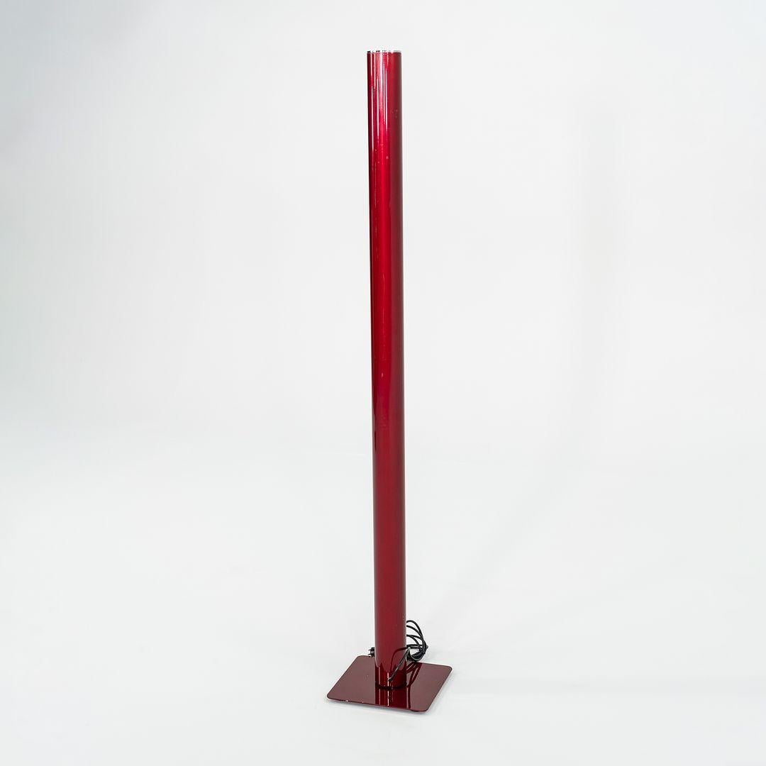 This is an Ilio LED Floor Lamp made with a red steel base and aluminum cylinder. This lamp was designed by Ernesto Gismondi and produced by Artemide in Italy. It dates to circa 2022 and is guaranteed as authentic. Condition is very good. There are