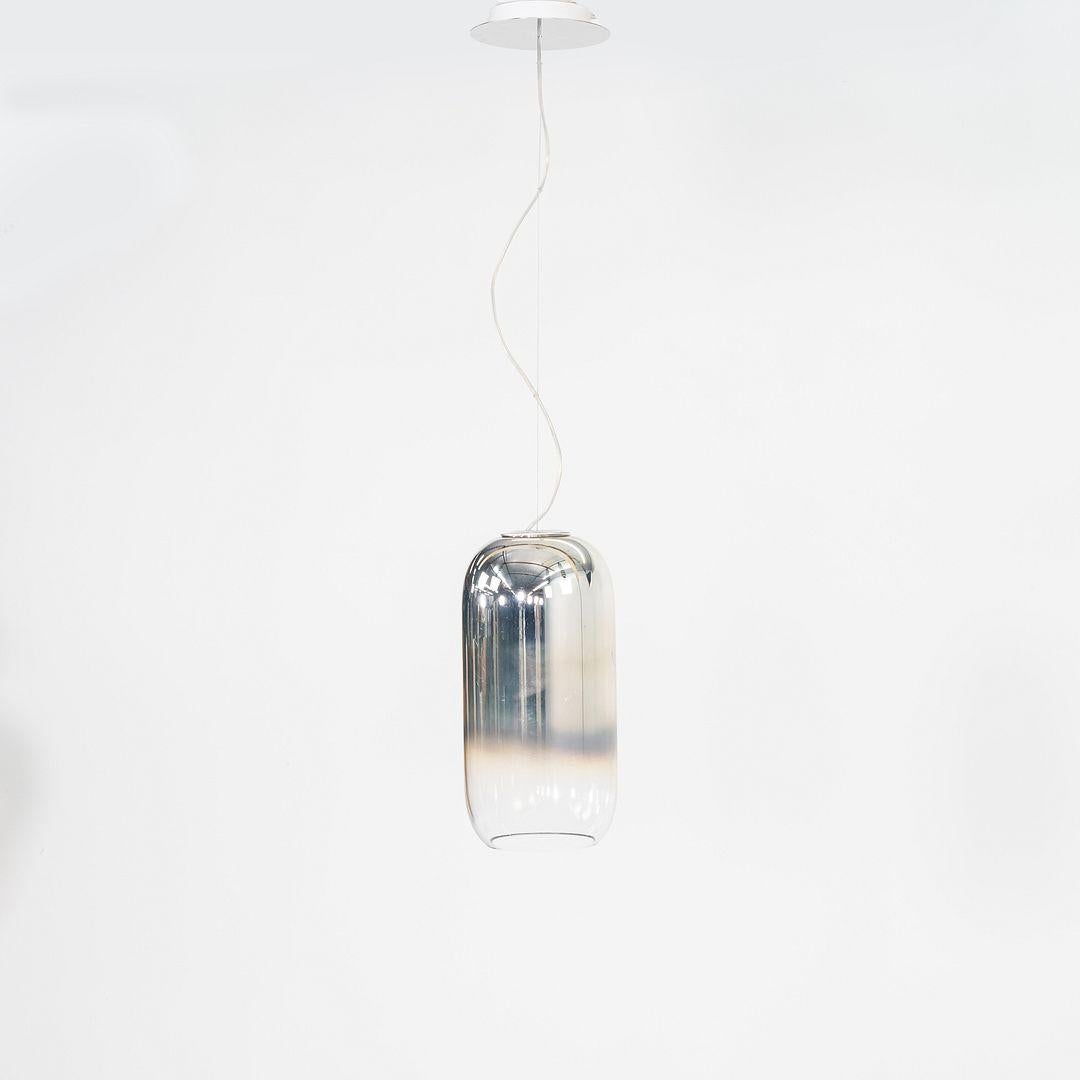Questa è una lampada a sospensione Gople, originariamente progettata da Bjarke Ingels Group nel 2010. Questo particolare esemplare è stato prodotto da Artemide in Italia nel 2022. La lampada è composta da vetro soffiato e alluminio ed è rifinita in
