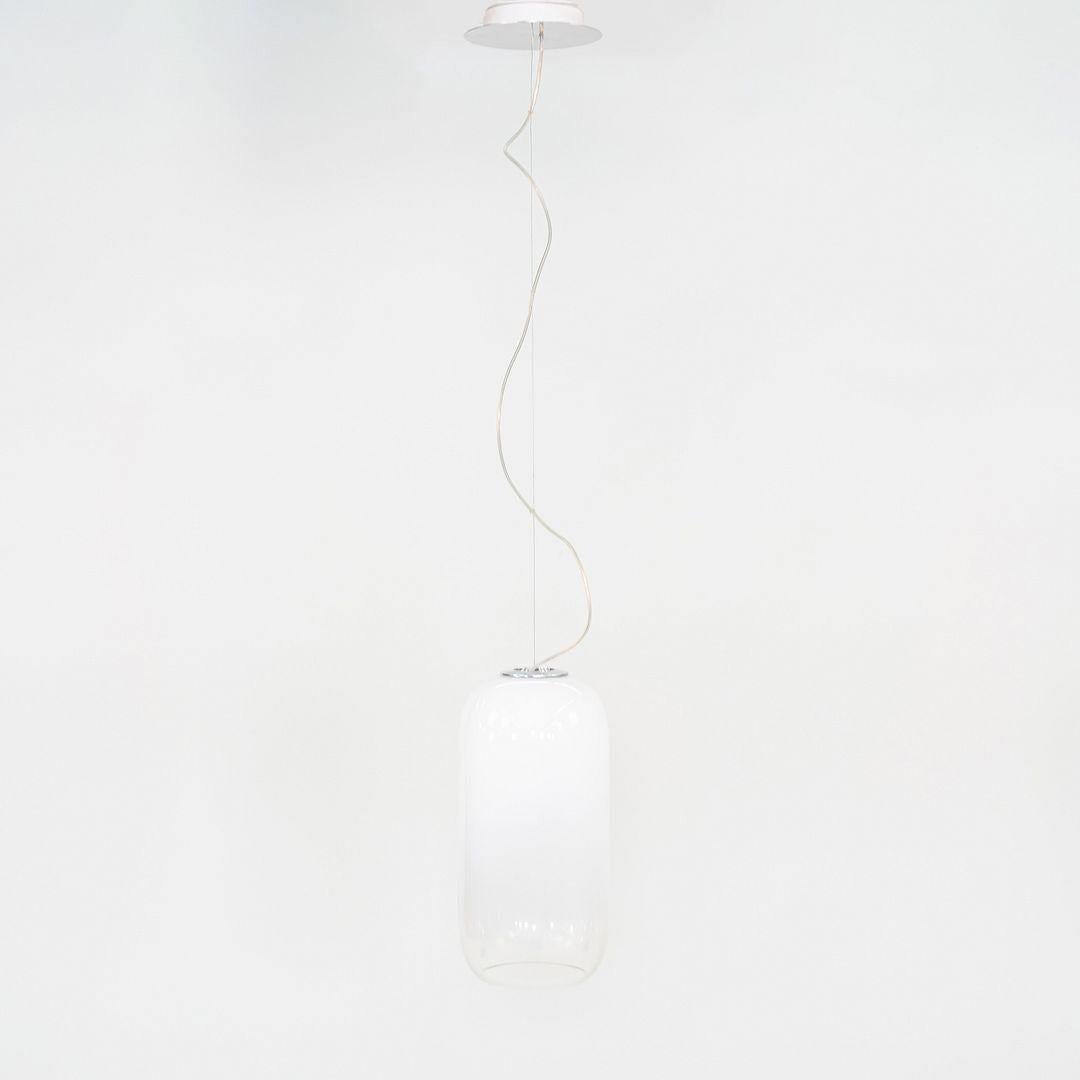 This is a Gople Suspension Pendant Lamp, originally designed by the Bjarke Ingels Group in 2010. This particular example was produced by Artemide in Italy C. 2022. The lamp is comprised of blown glass and aluminum, and is finished in white. It has