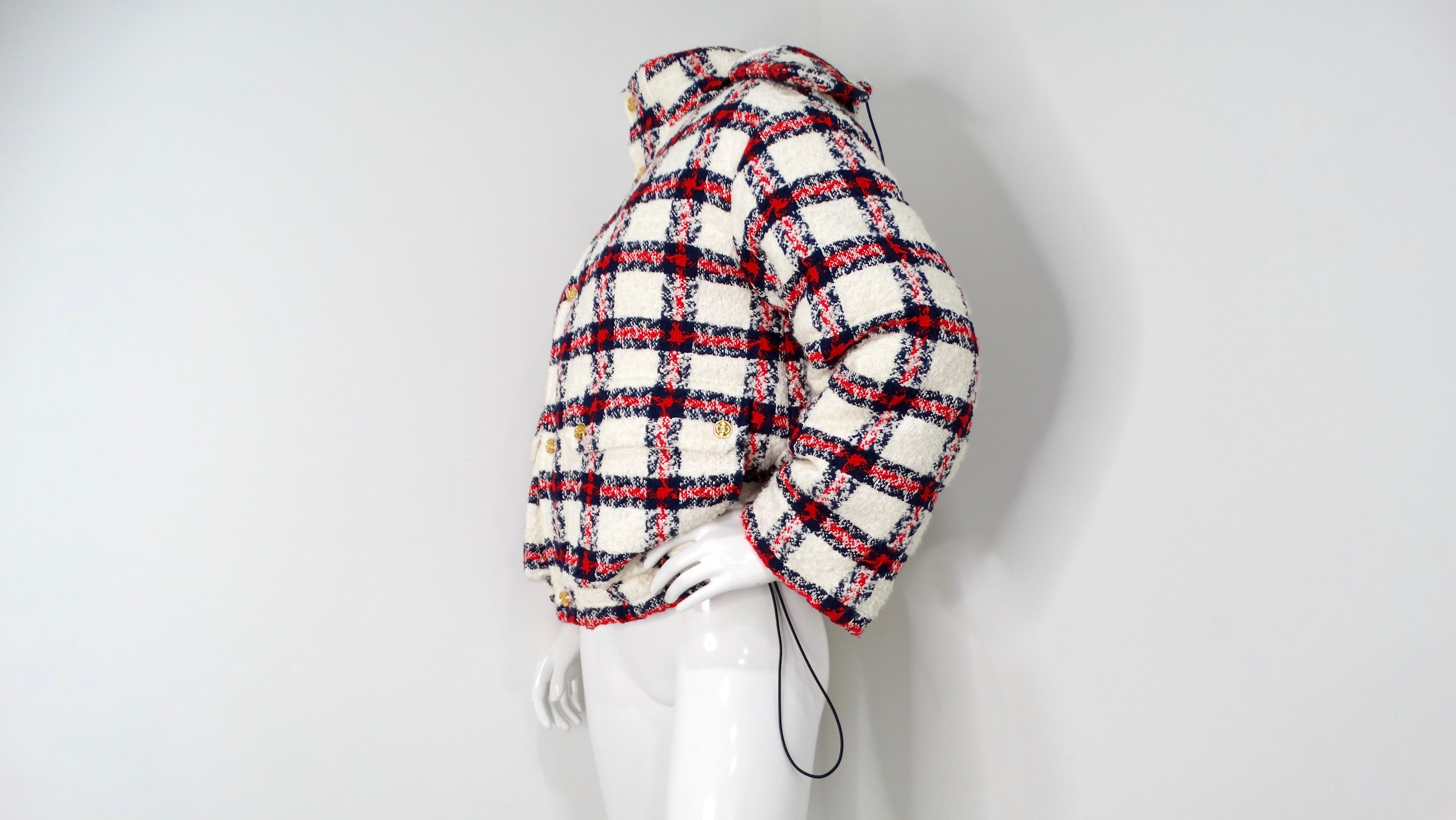 The 2022 Gucci Tweed Plaid Hooded Jacket is a standout piece that masterfully blends classic and contemporary elements. Crafted from a refined tweed, it showcases an eye-catching blue, red, and white plaid pattern adorned with luxurious gold-tone