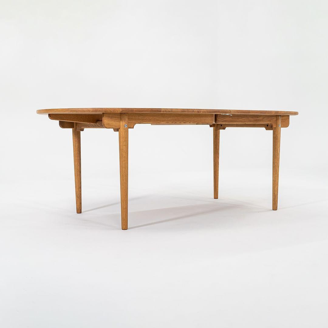 This is a CH338 dining table, designed by Hans Wegner and produced by Carl Hansen & Son in Denmark. This example was produced circa 2022 and is guaranteed as authentic. The piece includes two extension leaves made of oiled oak, and the table can