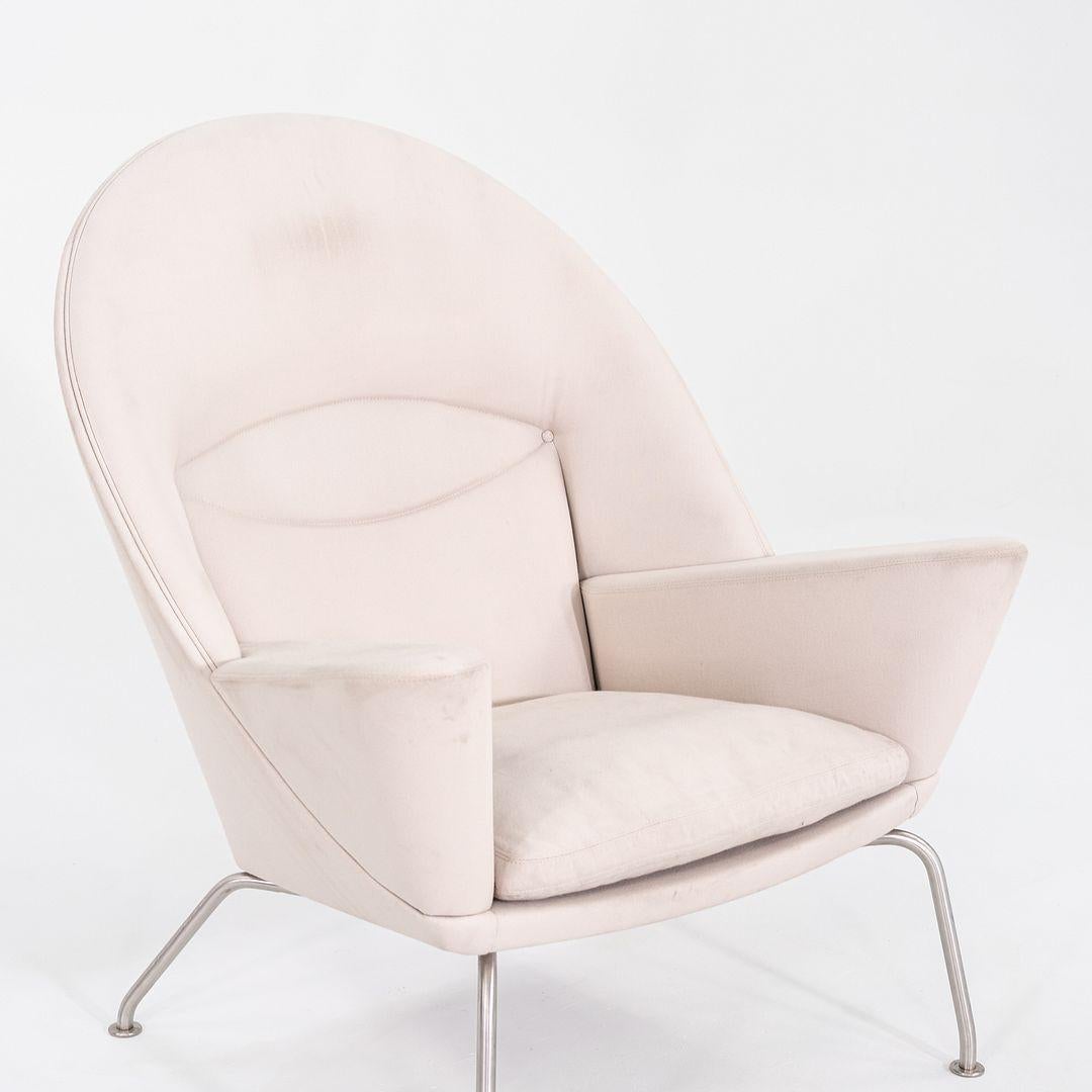Esta es una Silla de salón Oculus CH468, diseñada originalmente por Hans Wegner para Carl Hansen en 1960. Esta pieza en concreto se fabricó en Dinamarca en 2022. La silla se compone de un armazón de haya maciza, patas de acero y está tapizada en