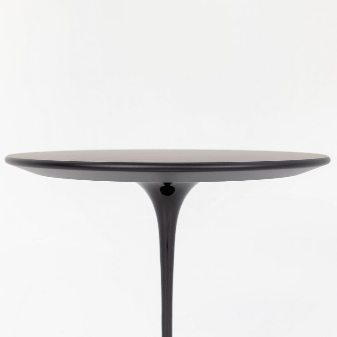 Il s'agit d'un guéridon Tulip, modèle 163TR, conçu à l'origine en 1956 par Eero Saarinen pour Knoll. Cette pièce a été produite en Italie en 2022. La base est formée de fonte d'aluminium moulée, avec une finition noire brillante. Le logo de