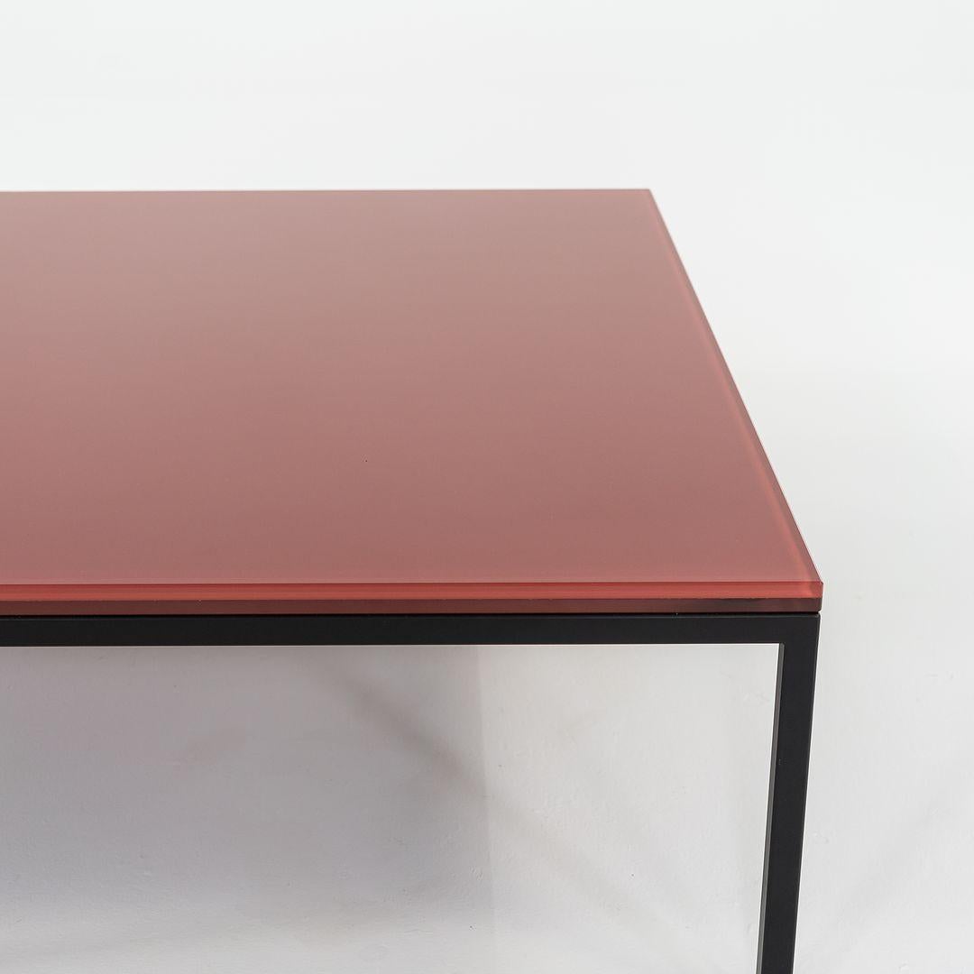 This is a Nana table, originally designed by Annabel Karim Kassar in 2021. This particular example was produced by Moroso in Italy circa 2023. The table is comprised of a steel base with a powder coat finish and a laminated glass top in Oxide Red
