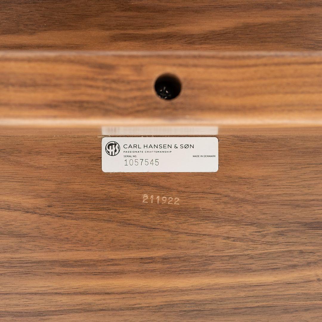 This is a BM1160 Hunting Table. This style was originally designed by Borge Mogensen in 1950, and this particular example was produced by Carl Hansen in Denmark circa 2023. The table is comprised of walnut and features stainless steel cross bars on