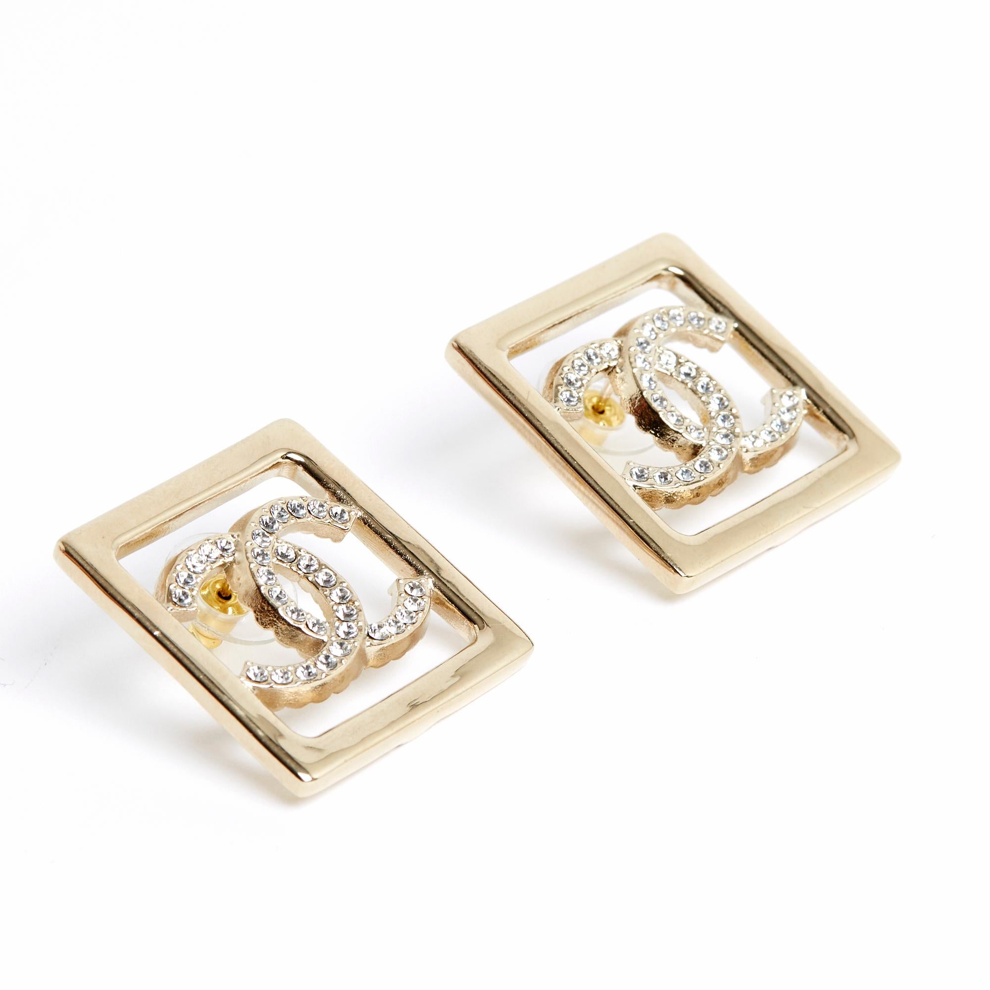 Chanel stud earrings in lightly gold-plated metal, with the motif of a square surrounding the CC symbol paved with small white rhinestones. Width 3.1 cm x height 3.1 cm. The earrings are delivered without invoice or original packaging but they are