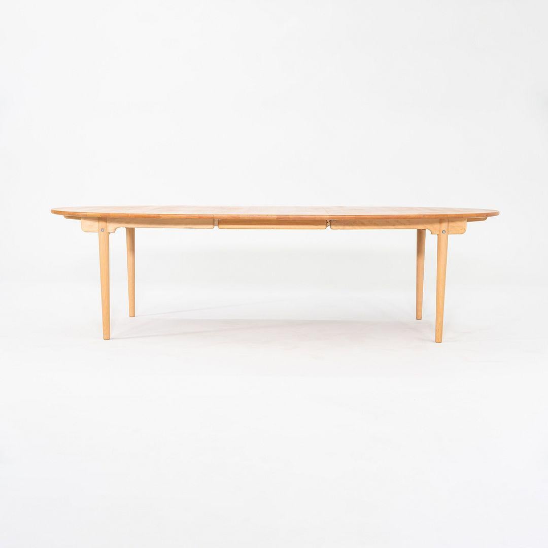 This is a CH338 dining table, originally designed by Hans J. Wegner in 1962. This example was produced by Carl Hansen in Denmark in 2023. This CH338 dining table is made of beech with a lacquer finish. The table can expand to fit two leaves. This