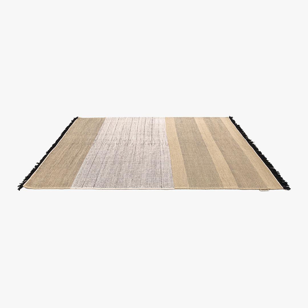 Alfombra Tres Rayas tejida a mano con lana y algodón en tonos negros y beige. La alfombra, diseñada por Nani Marquina y producida por Nanimarquina en la India, data de hacia 2023 y está garantizada como auténtica. El estado es como nuevo (o si no,