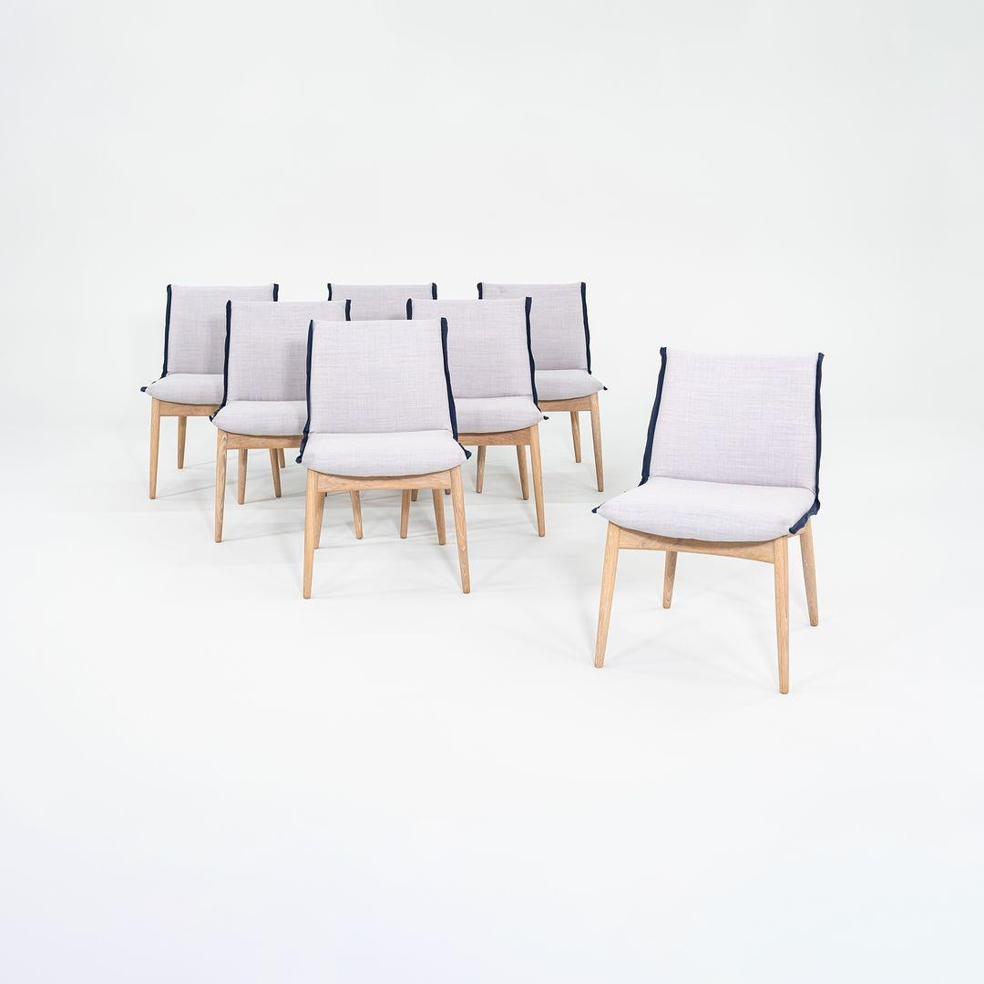 Si tratta di un set di sette sedie da pranzo EOO4 Embrace con struttura in legno massiccio di quercia e seduta rivestita in tessuto blu con finiture blu scuro. La sedia è stata progettata da EOOS e prodotta da Carl Hansen & Son in Danimarca. Risale