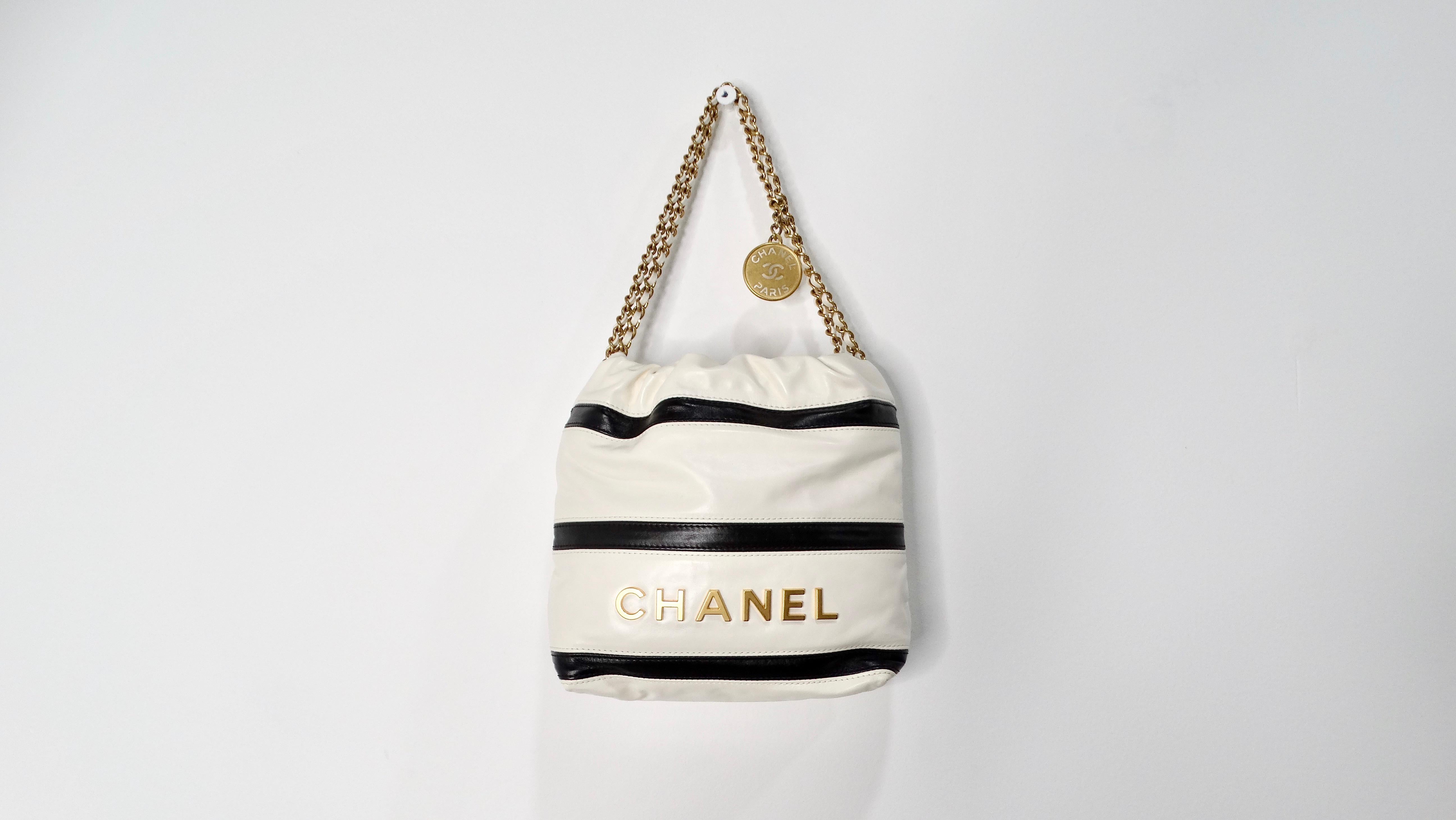 Introducing the 2024 Chanel Mini 22 Black & White Striped Shiny Calfskin Hobo Bag—a stunning embodiment of modern elegance and timeless sophistication. Crafted from luxurious shiny calfskin leather, this hobo bag features a striking black and white
