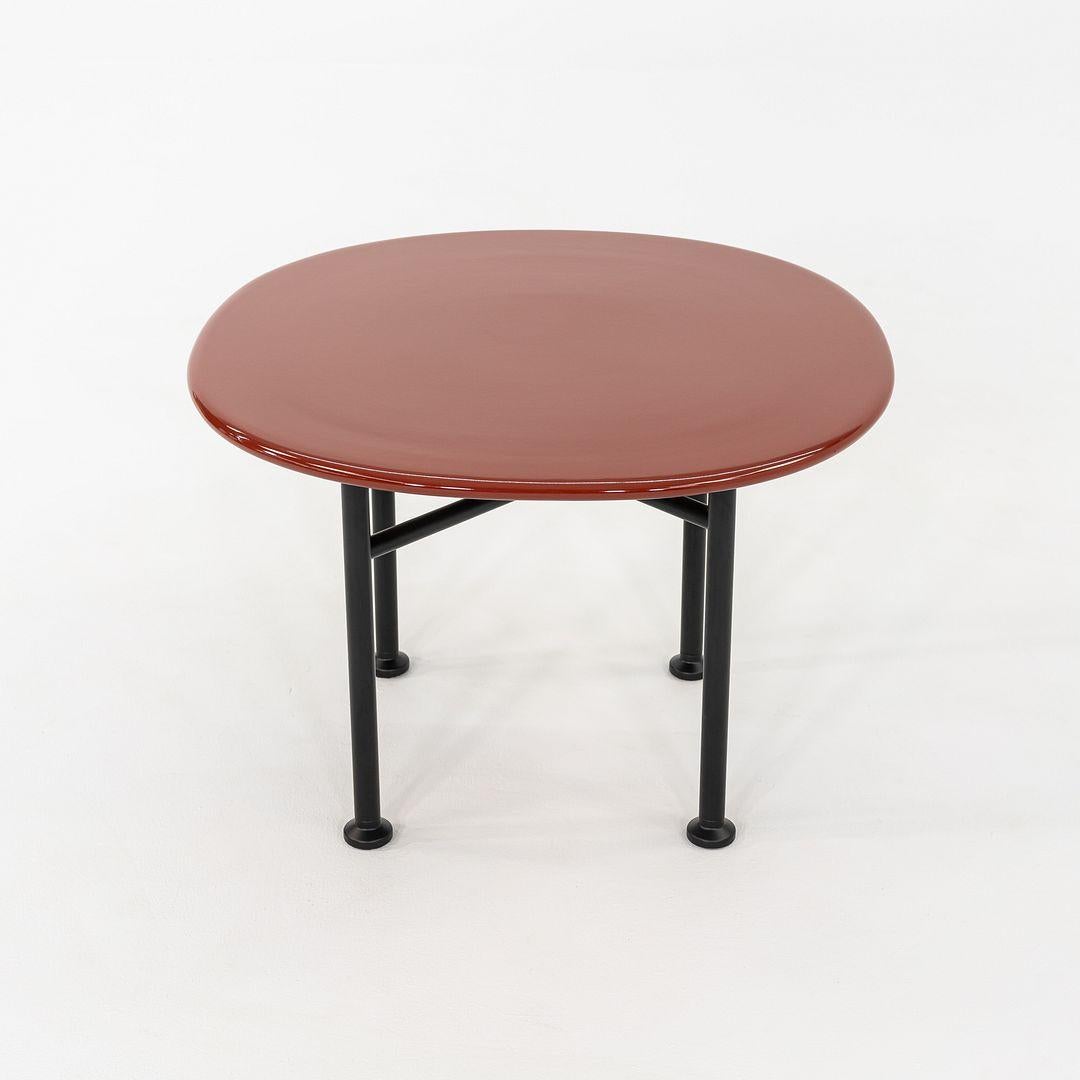 Ésta es una Mesa baja Carmel, diseñada originalmente por OEO Studio para Gubi. Este ejemplo concreto se fabricó en Dinamarca en 2024. La mesa se compone de una base de metal y un tablero de cerámica de color rojo roca. La mesa Carmel fue el primer