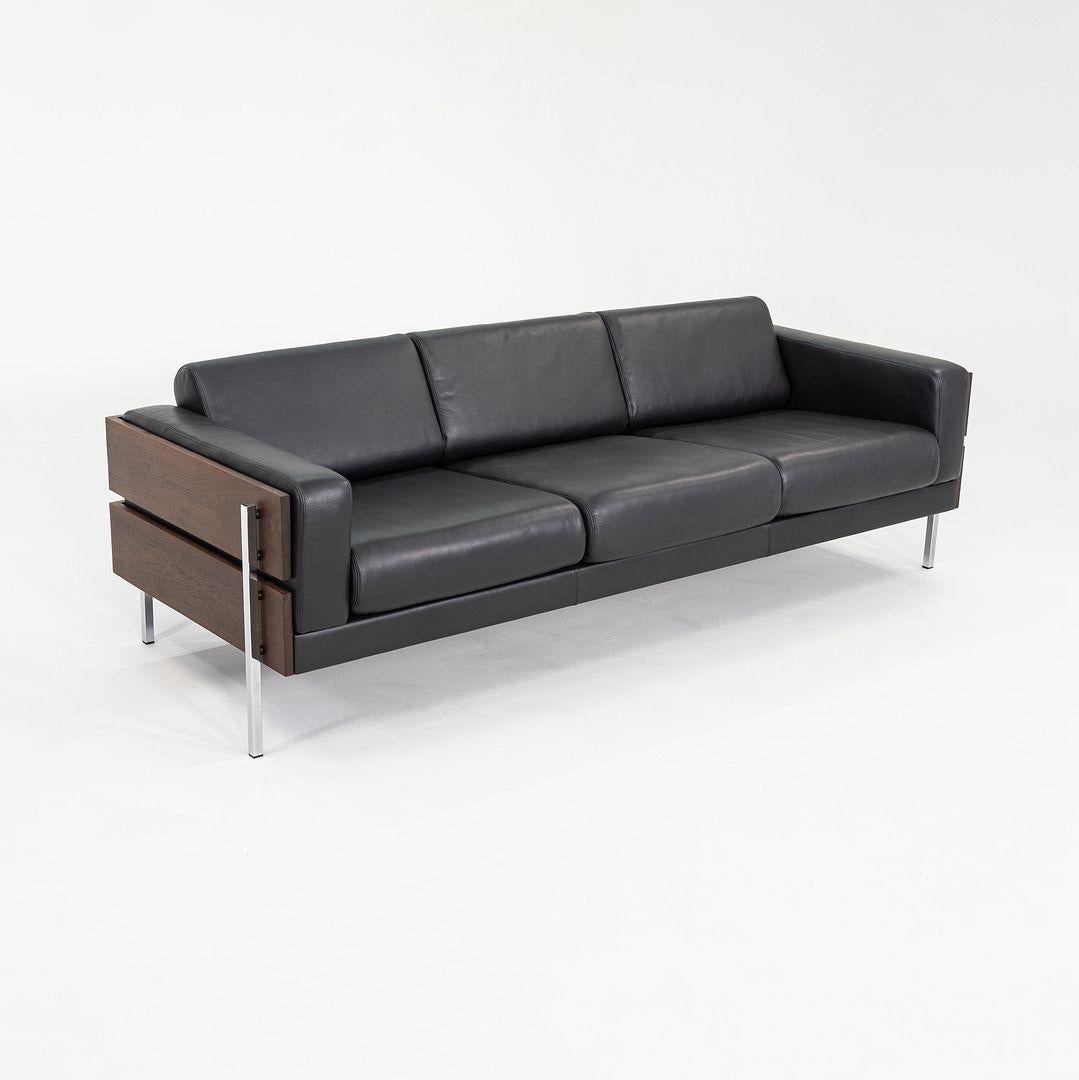 This is a Three Seat Forum Sofa, originally designed by Robin Day in 1964. This particular example was produced by Case Furniture in the United Kingdom in 2024. Its design features a walnut frame, chrome plated legs, and cushions upholstered in