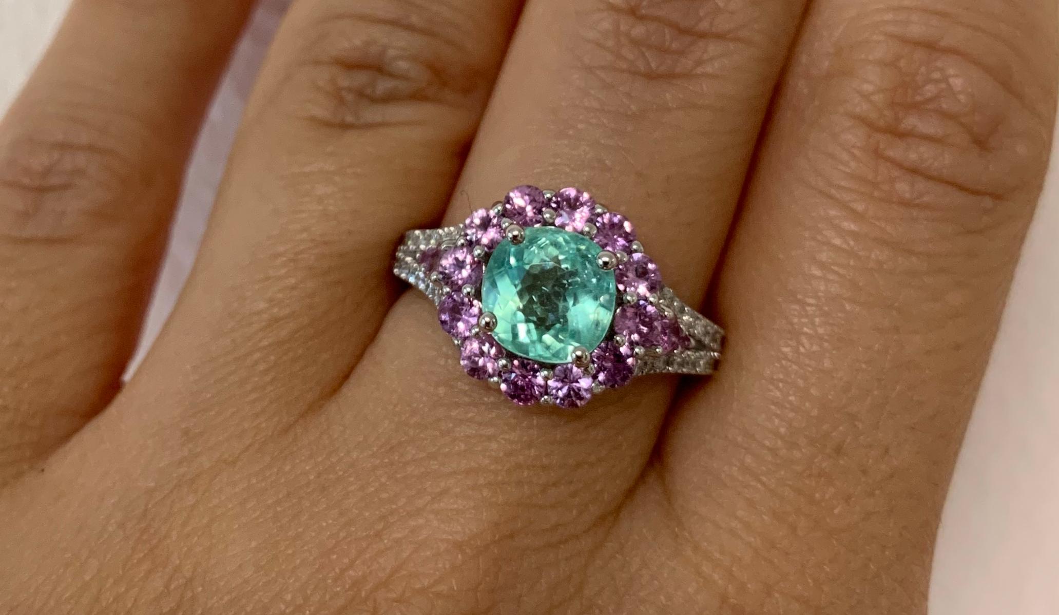 Material: 14k White Gold 
Center Stone Details: 2.03 Carat Cushion Cut Paraiba Tourmaline Measuring 7.2mm
Stone Details: 16 Round Pink Sapphires at 1.12 Carats
Diamond Details: 32 Brilliant Round White Diamonds at Approximately 0.25 Carats -