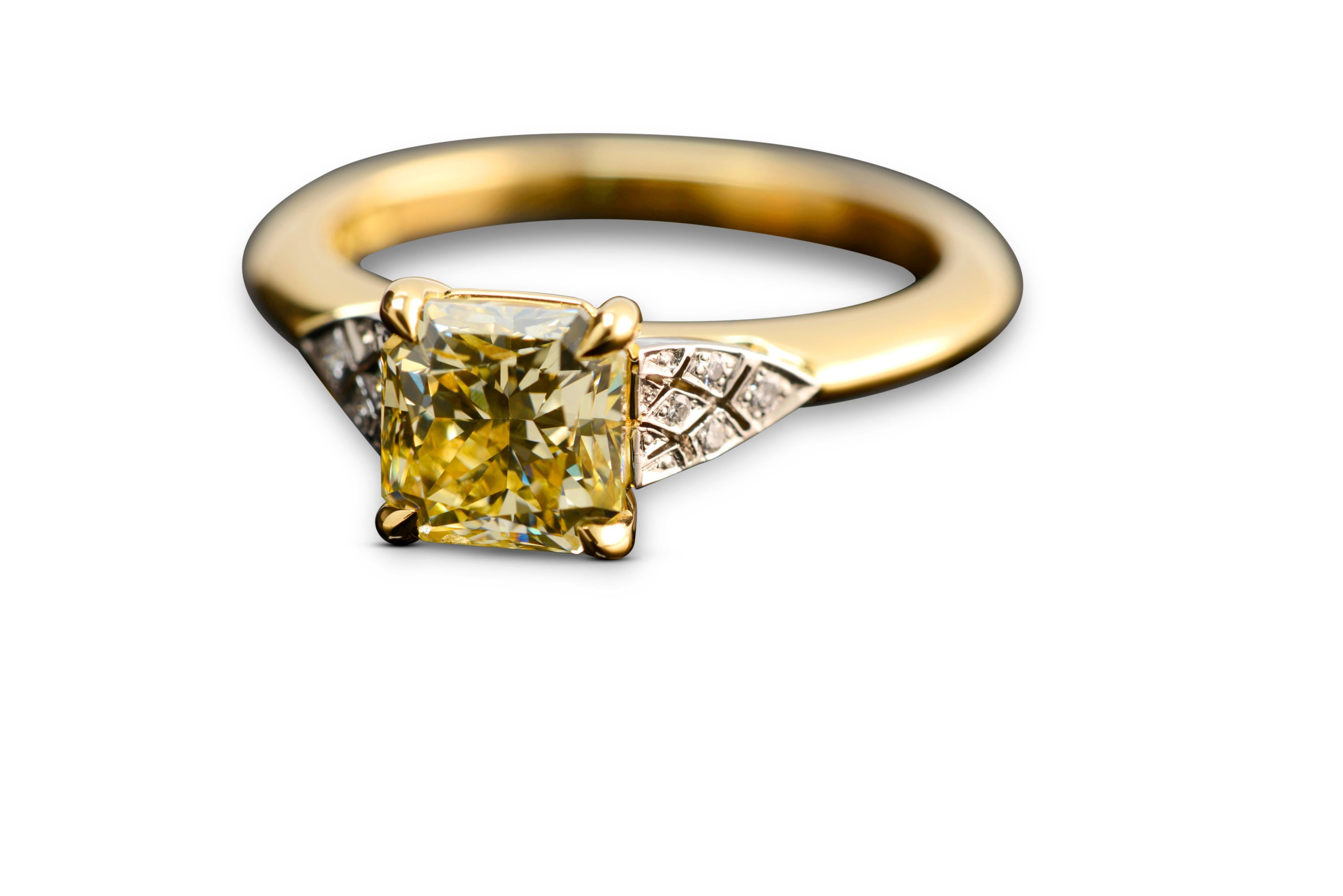 Handmade by Nicky Burles is a 2.03 carat fancy yellow radiant cut diamond solitaire engagement ring. This two tone beauty features an 18 karat yellow gold 4 claw setting and soft knife edge band. The shoulders of the ring are detailed with an