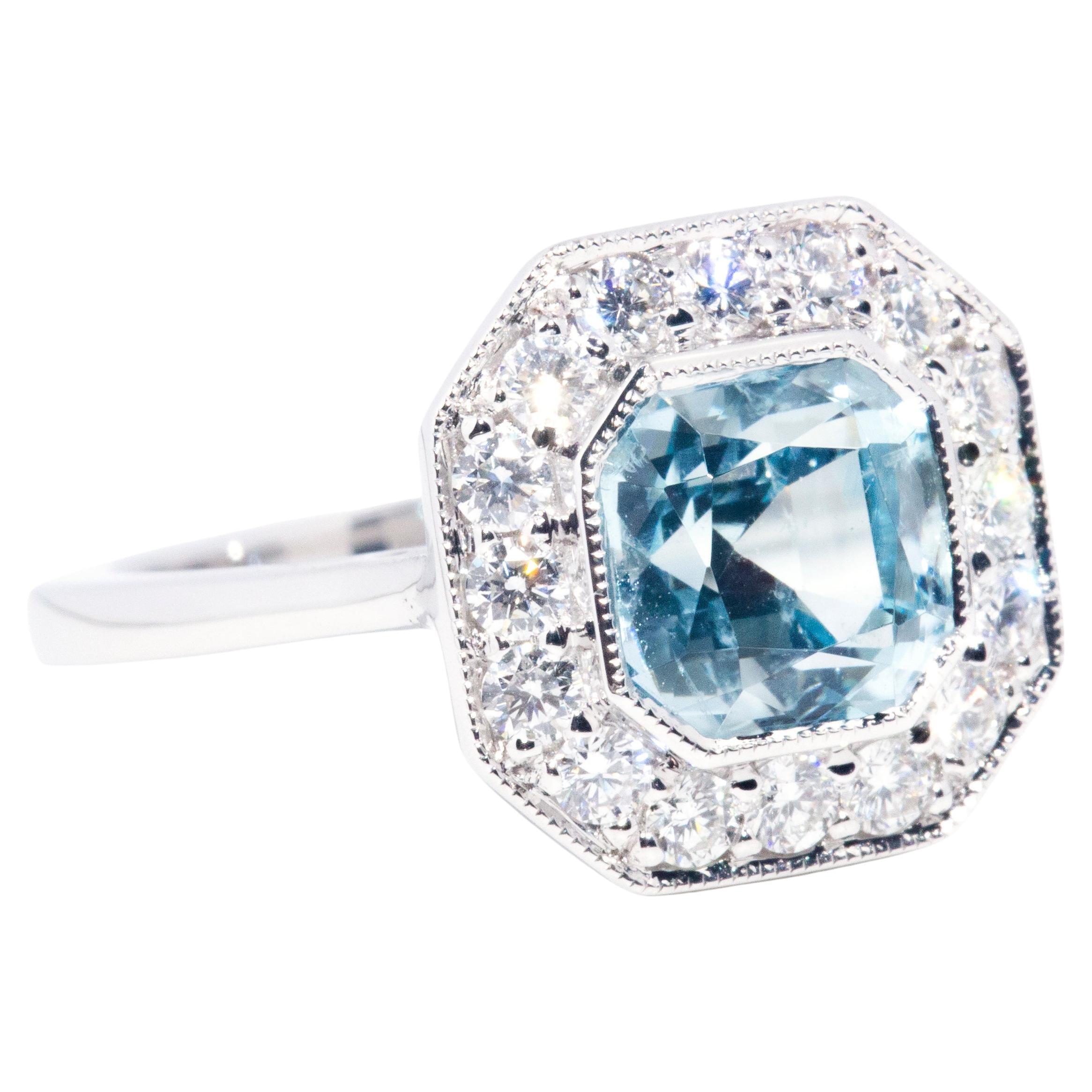 Forged in 18 carat white gold, this captivating halo ring features a breathtaking 2.04 carat bright light blue Asscher cut aquamarine resting in a captivating halo gallery and encompassed by a shimmering border of round brilliant cut diamonds. This