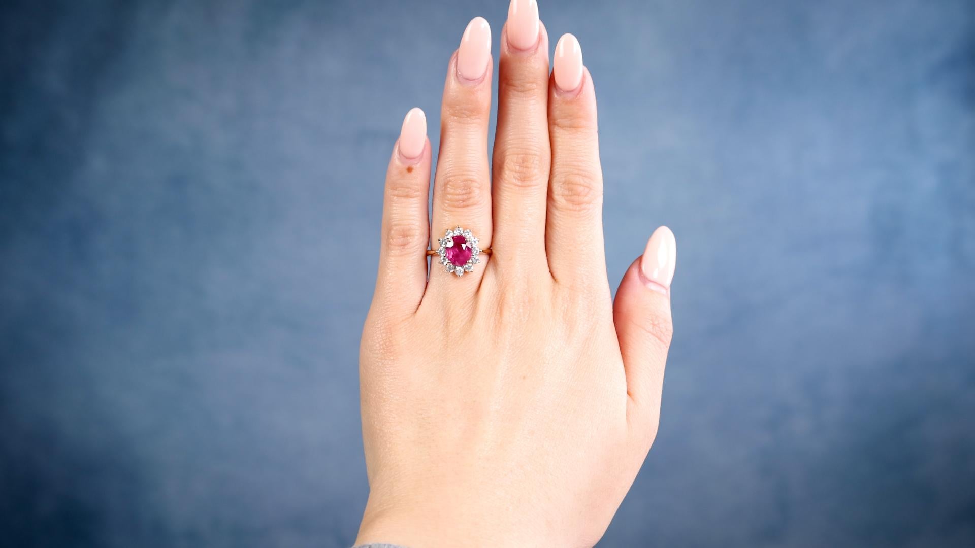 Ein 2,04 Karat Rubin und Diamant 18k Gelbgold Cluster Ring. Mit einem ovalen Rubin im Mischschliff von 2,04 Karat. Akzentuiert durch 12 runde Diamanten im Brillantschliff mit einem Gesamtgewicht von 0,95 Karat, eingestuft als farblos, Reinheit