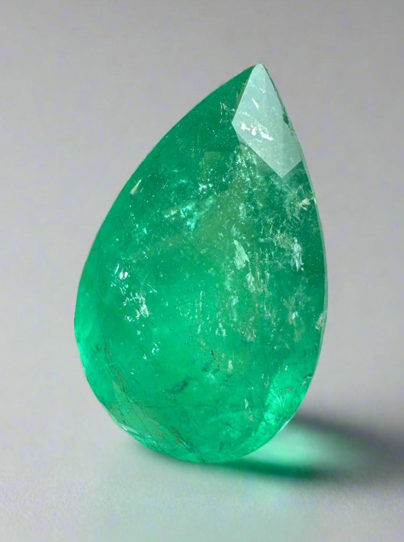 Stone: Emerald
Weight: 20.43-carats
Shape: Pear Cut
Clarity: Transparent
Luster: Very Good
Color: Medium Deep Green
Measurements: 23.92mm x 15.50mm x 9.87mm
Geographic Origin: Colombia
Treatment: Natural, Oiling

Comments: Due to their growth