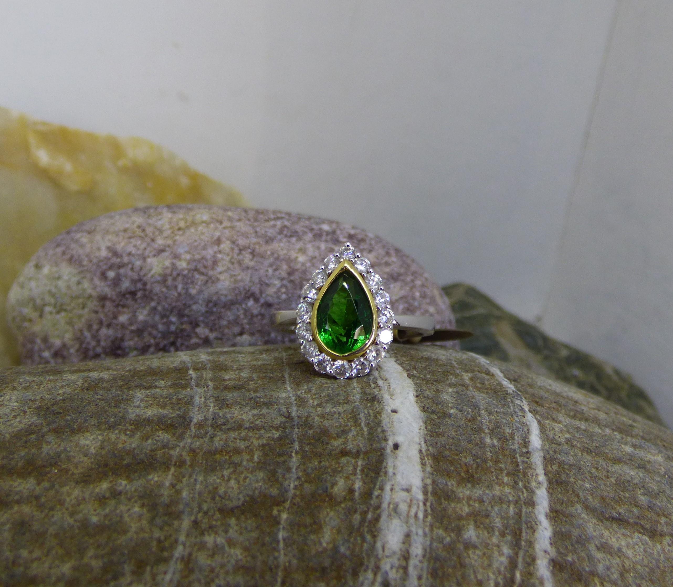 A brilliantly bright and colourful Tsavorite Garnet Pear stone is 10X6mm weighing 2.04ct.  This lovely Garnet is surrounded by 16 Diamonds with a total Diamond weight of .59ct.  The ring is handmade in 18K white gold with the Garnet bezel set in 18K