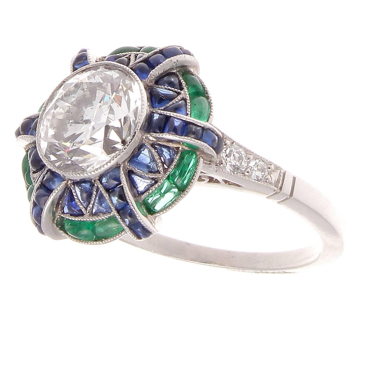 Creativity expressed through superior abstract design filled with colorful gemstones. Featuring a 2.05 carat old European cut diamond that is E color, SI2 clarity surrounded by galaxies of calibrated royal blue sapphires and forest green emeralds.