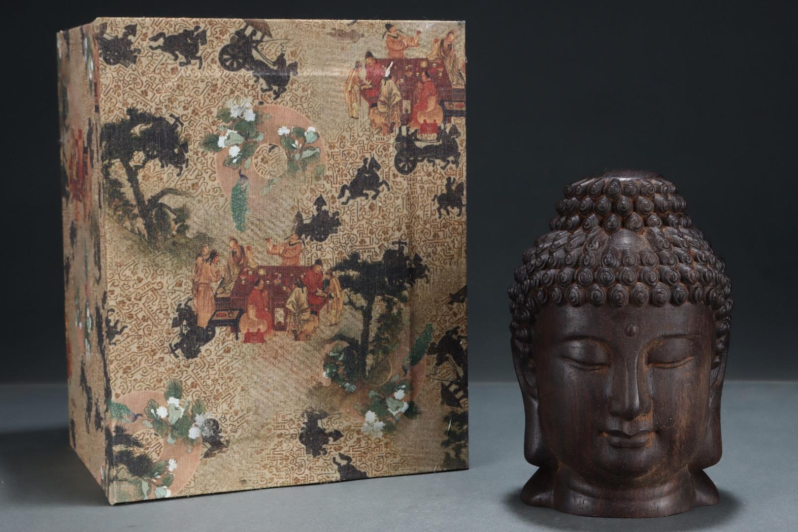This Vintage Asian Agarwood Engraving of a Buddha Head is a finely detailed and spiritually rich piece, carved from precious natural agarwood, renowned for its fragrant aroma and revered status in traditional Asian spirituality.

The serene Buddha
