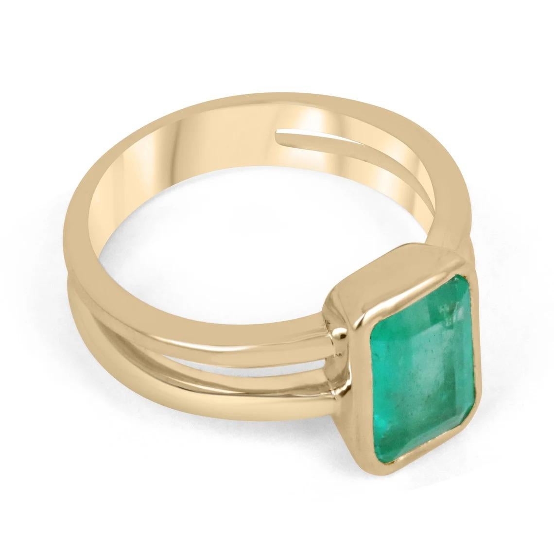 Displayed is a stunning emerald solitaire engagement or right-hand ring in 14K yellow gold. This gorgeous solitaire ring carries a gorgeous 2.05-carat emerald in a bezel setting. Fully faceted, this gemstone showcases excellent shine and beautiful,