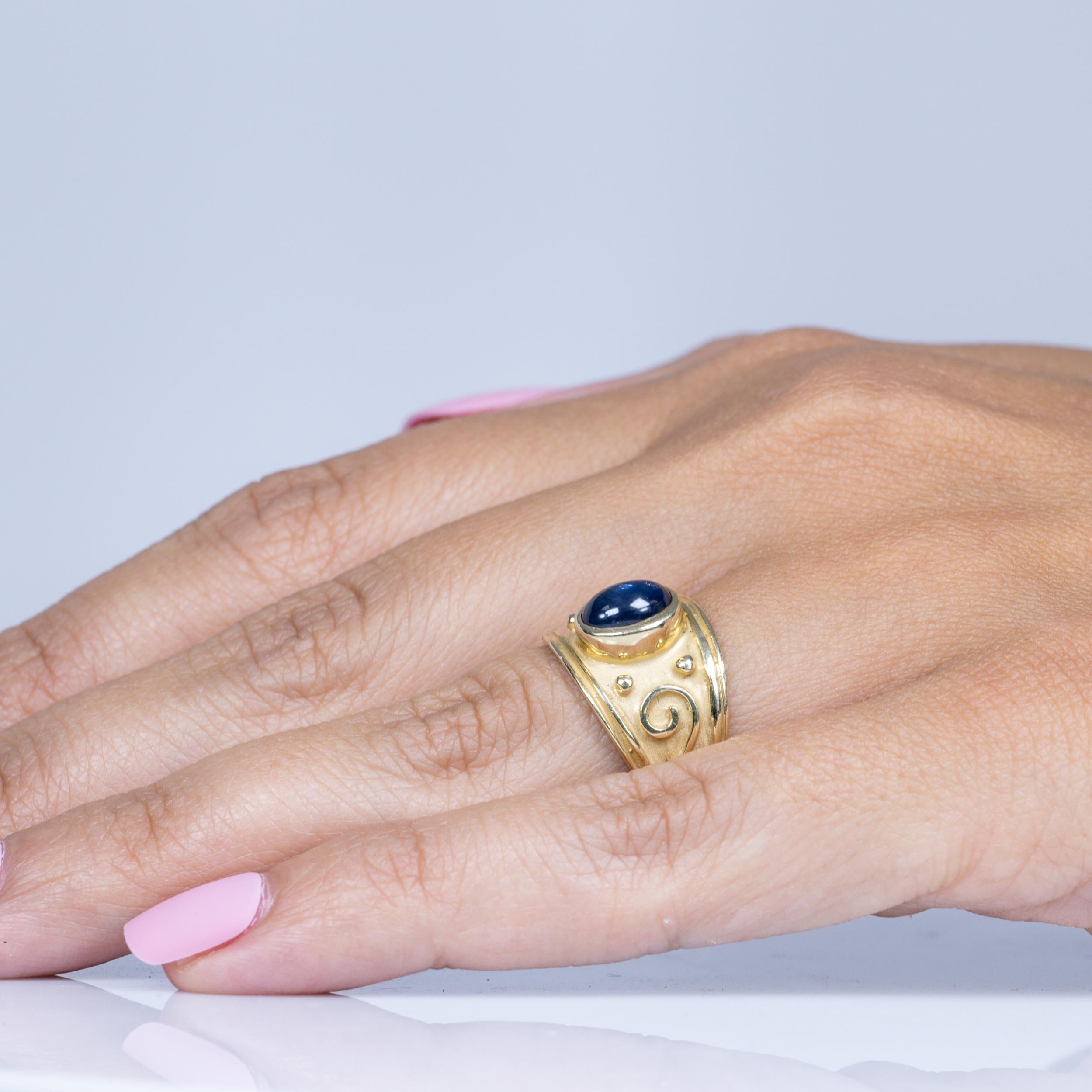 Dieser bezaubernde Ring ist mit einem 2,05-karätigen blauen Saphir-Cabochon besetzt, der in ein elegantes, satiniertes 14-karätiges Gelbgoldband eingefasst ist. Der tiefblaue Farbton des Saphirs kommt durch die weiche, matte Textur des Goldes