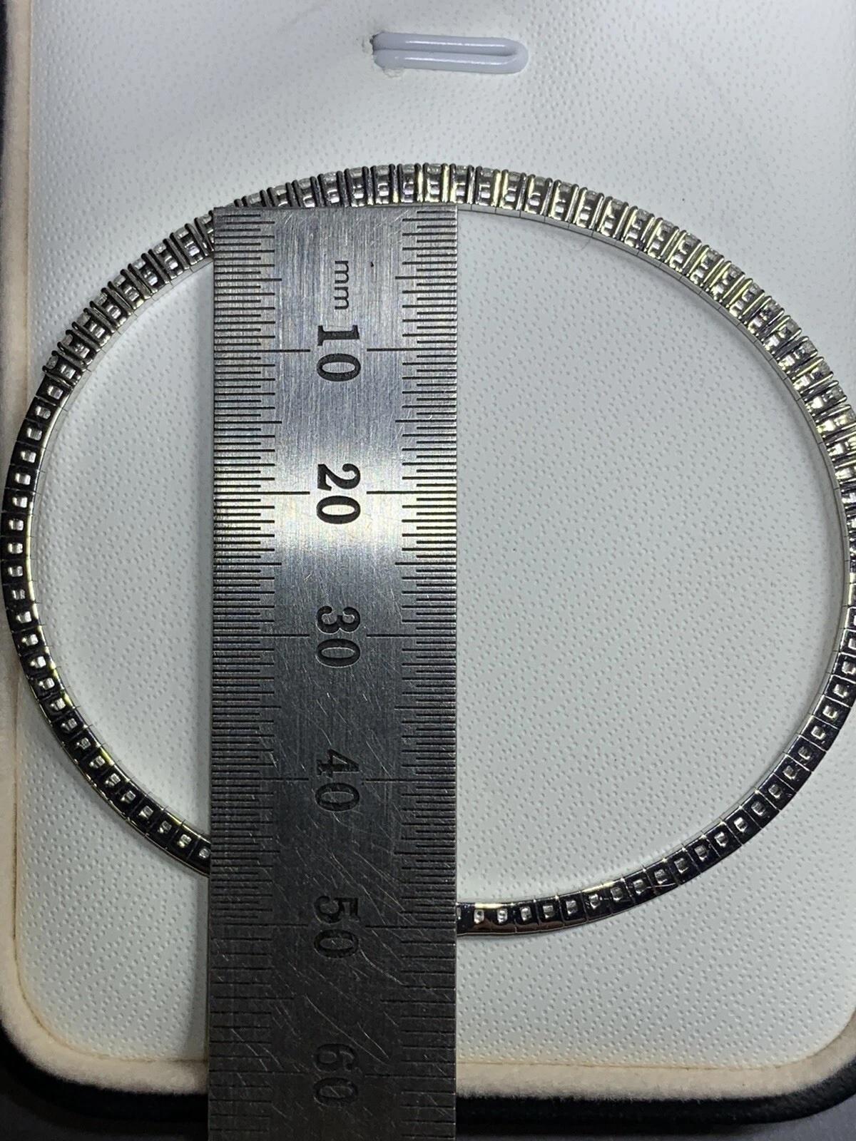 Esta exquisita pulsera tenis de diamantes es una auténtica obra maestra de la alta joyería. Realizado en oro blanco de 18 ct, presenta un impresionante diamante de 2,05 ct en talla brillante, rodeado de diamantes naturales de 2,05 ct con una