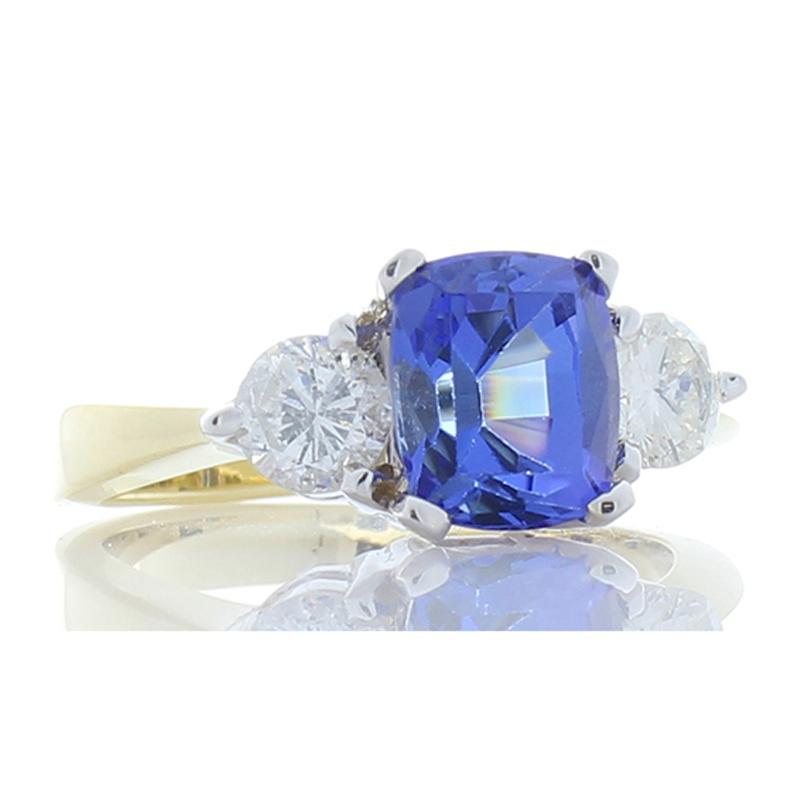 This dazzling ring features a gorgeous 2.06 carat - 7.80 x 6.60 millimeter tanzanite center. The gemstone is illuminating and and from the foothills of Mt. Kilimanjaro in Tanzania. The color is a vivid violet-blue. The center is accented by