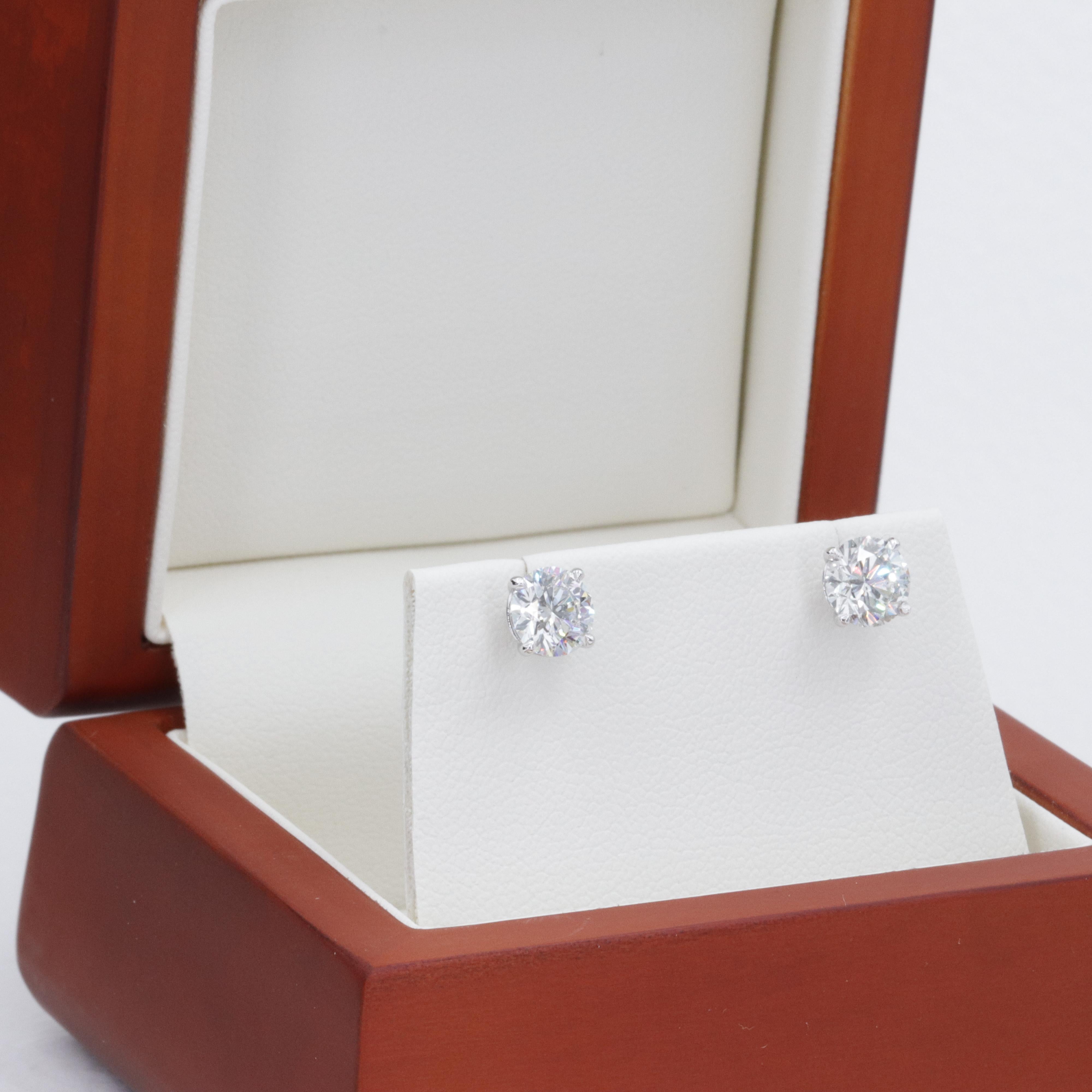 A beautiful pair of well matched round brilliant cut natural diamonds weighing 2.06 carats, with accompanying reports from the Gemological Institute of America (GIA) grading the diamonds as a bright white H & I in color with eye clean SI1 & SI2