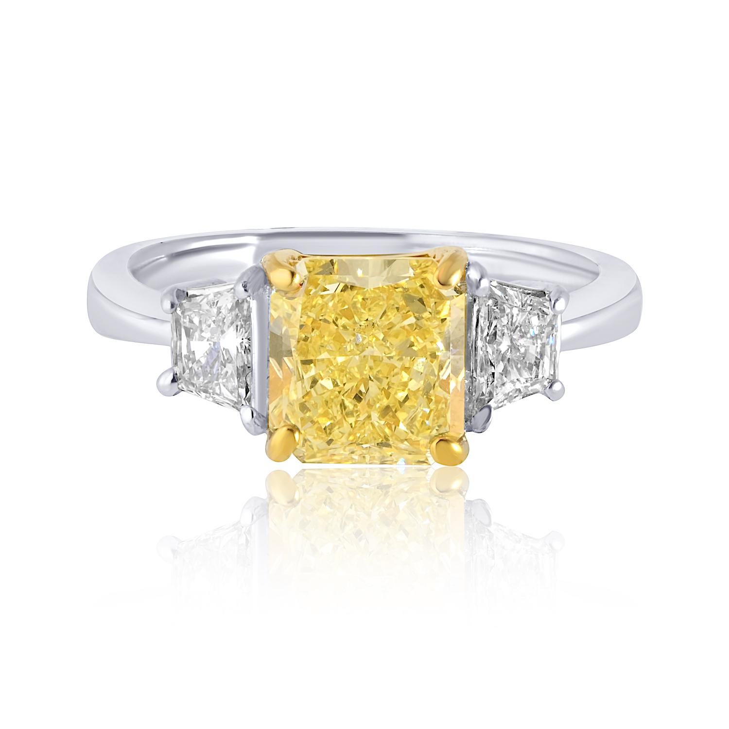 Cette exquise bague de fiançailles fabriquée à la main met en valeur un superbe diamant Fancy Yellow de 2,07 carats à taille radiante, certifié par le GIA pour sa couleur et sa brillance exceptionnelles. 

La pierre centrale est flanquée de deux